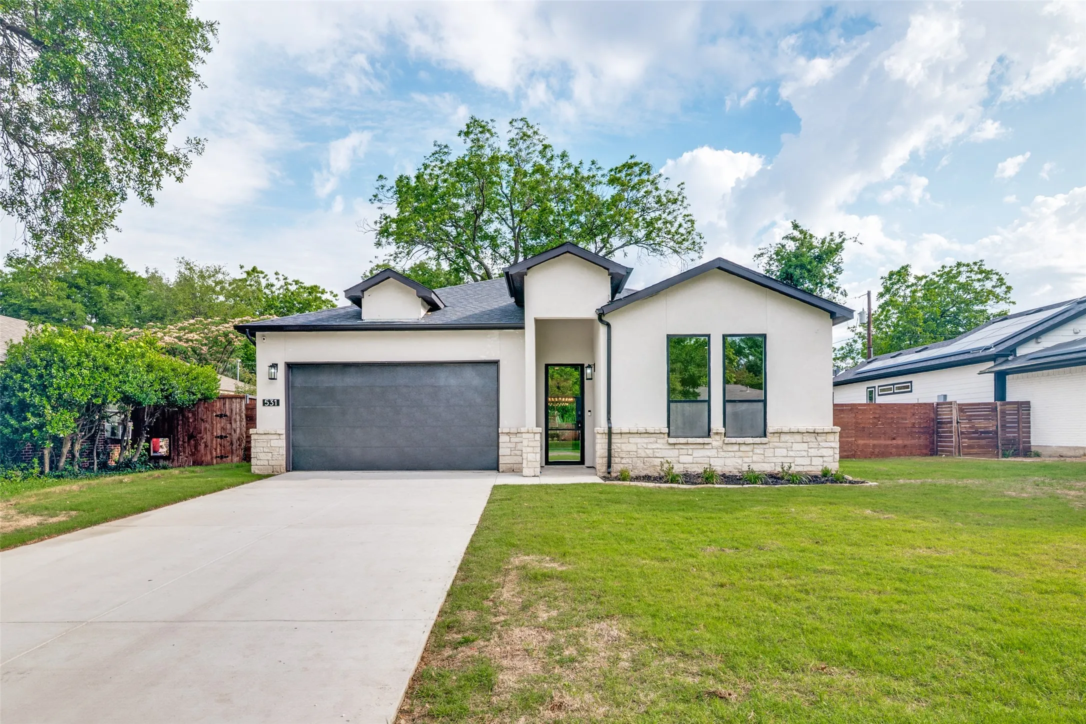 Contemporary facade featuring a light-colored stucco exterior, dark trim, and a dark garage door