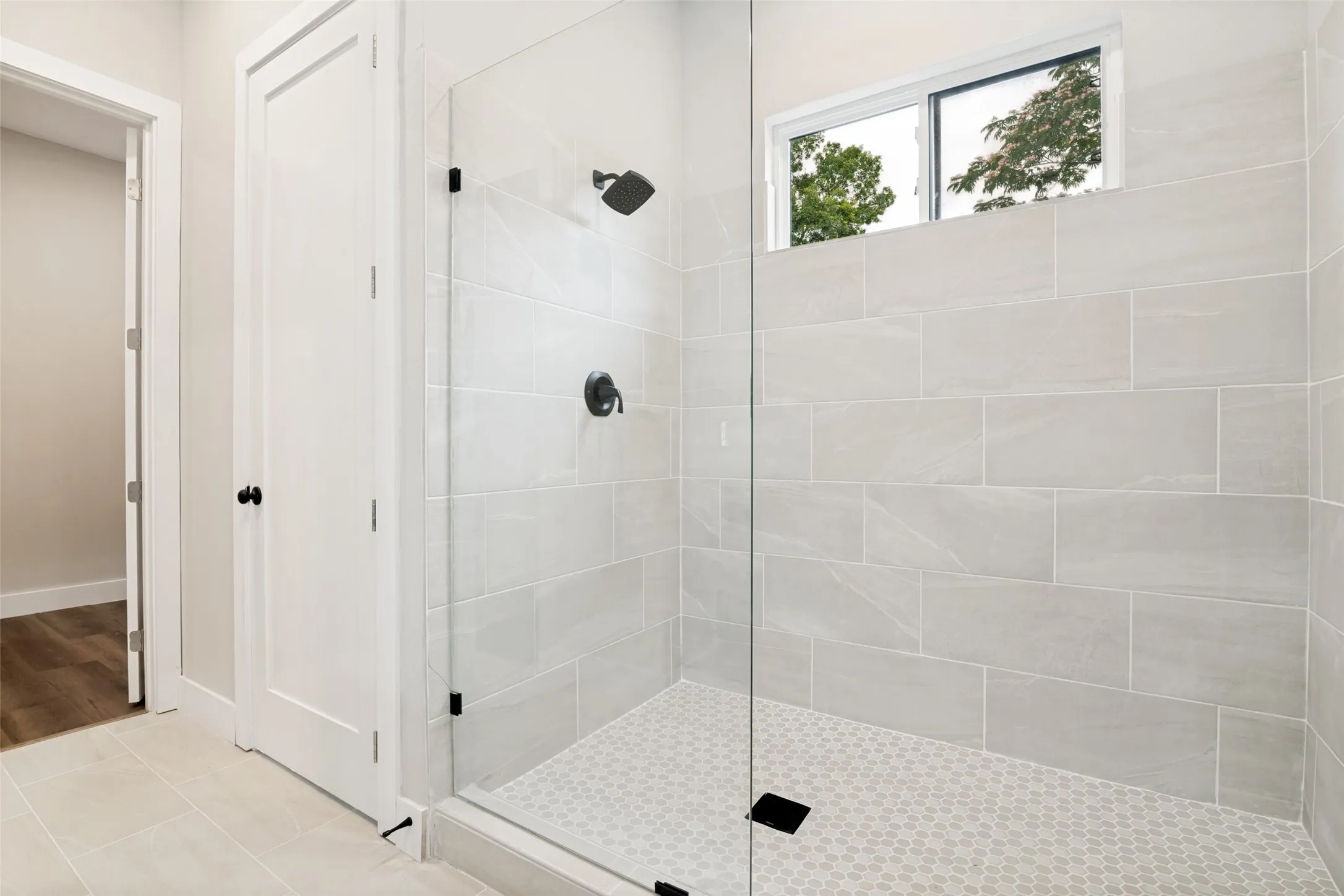 Contemporary walk-in shower featuring a frameless glass enclosure and a matte black shower system