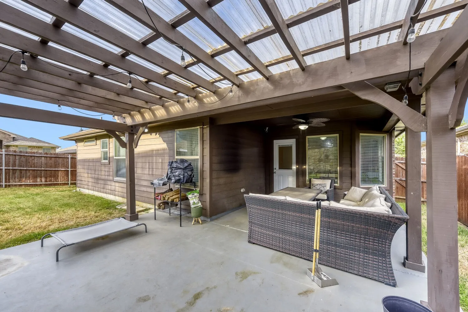 Covered patio featuring a wood pergola with translucent roofing and string lighting