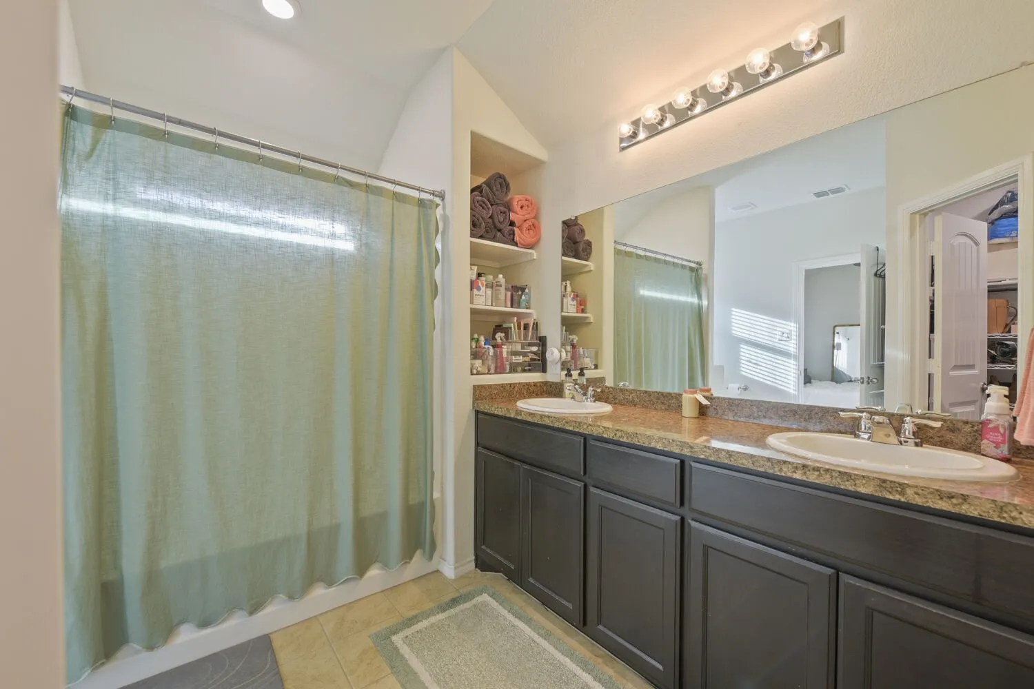 Double vanity with brown speckled countertop, recessed sinks, and dark cabinetry