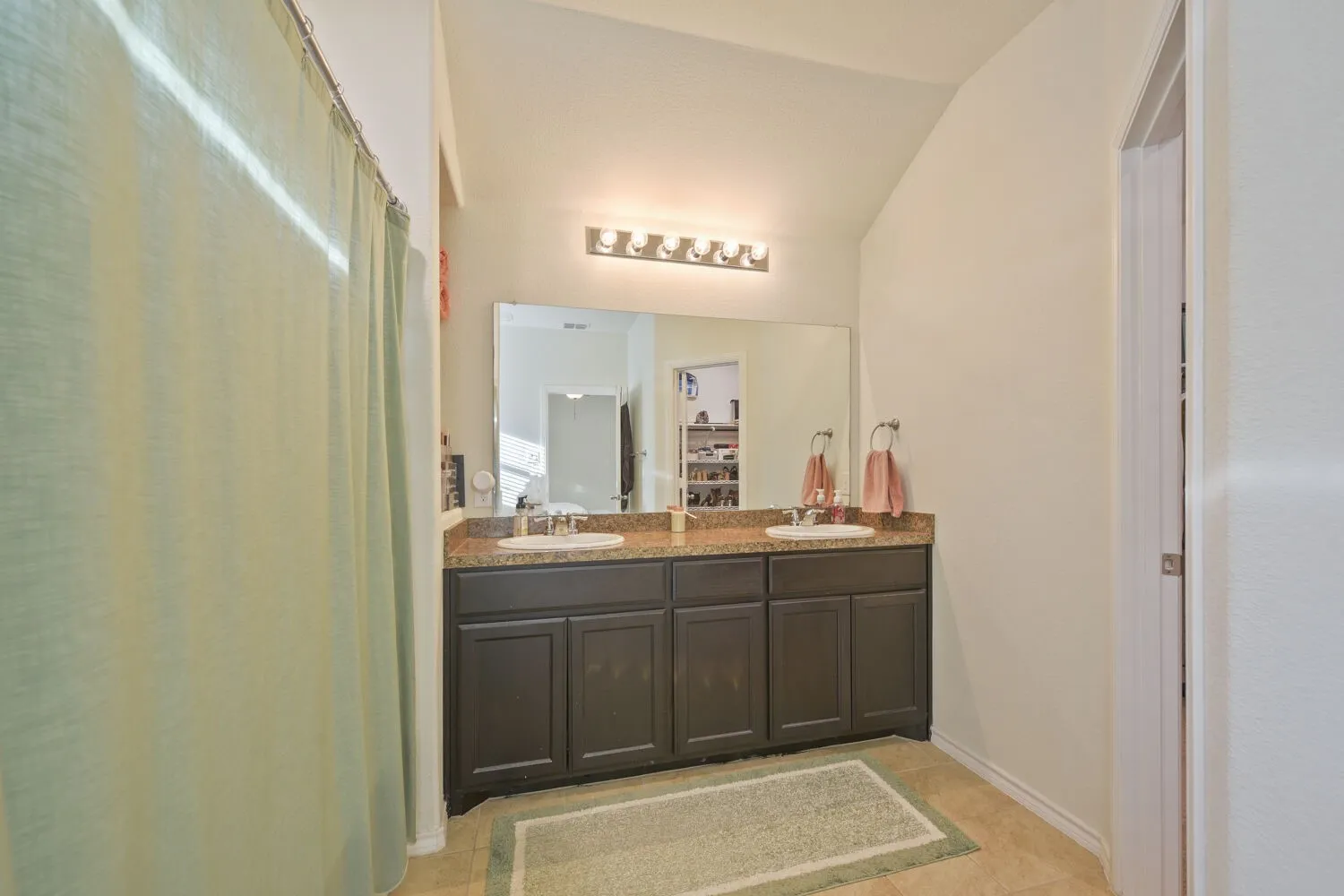 Bathroom featuring a double vanity with dark cabinetry, granite-finish countertop, and integrated sinks