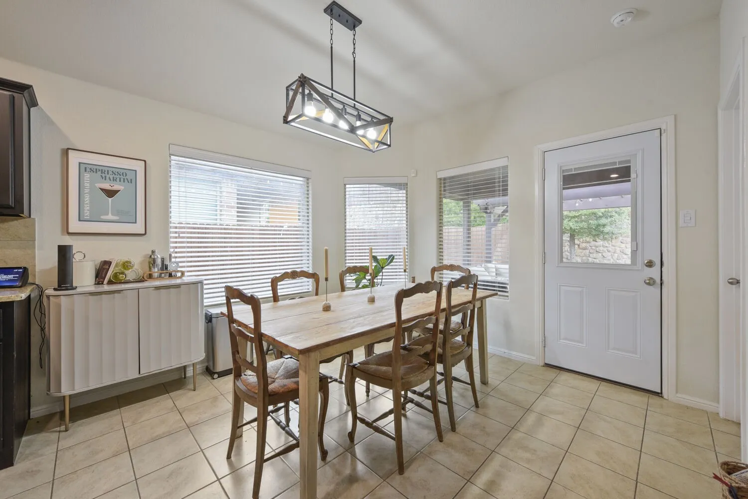 Dining area featuring large windows, neutral tile flooring, a built-in pantry door, and a glass-paneled exterior door