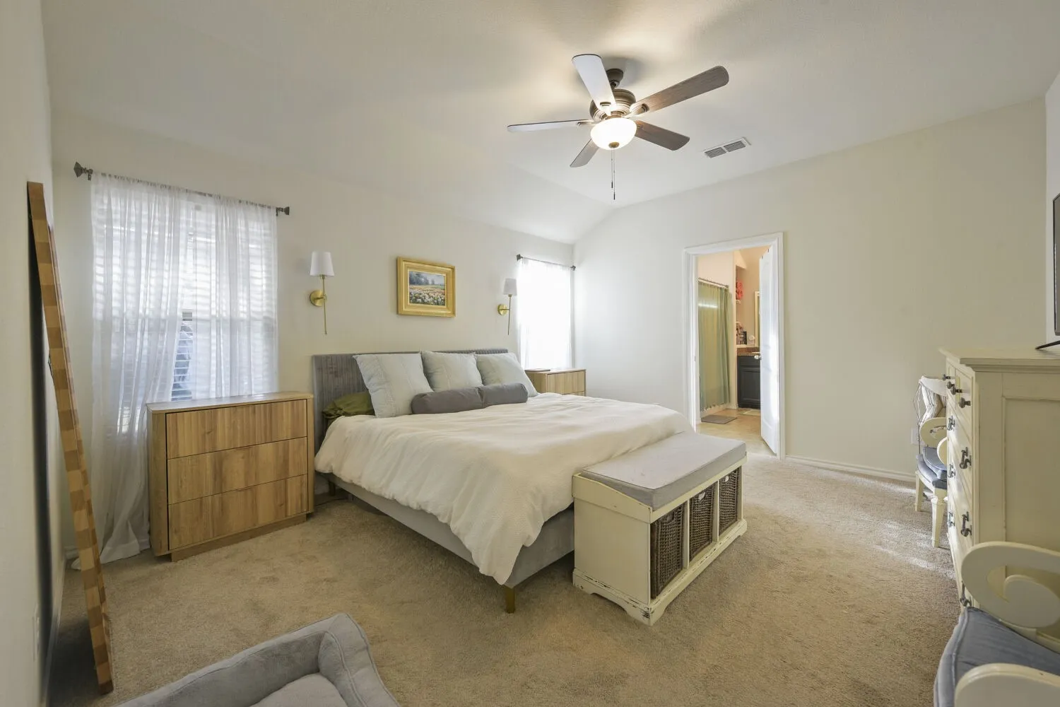 Carpeted interior room featuring a vaulted ceiling with a ceiling fan, two windows with blinds, and wall-mounted sconces