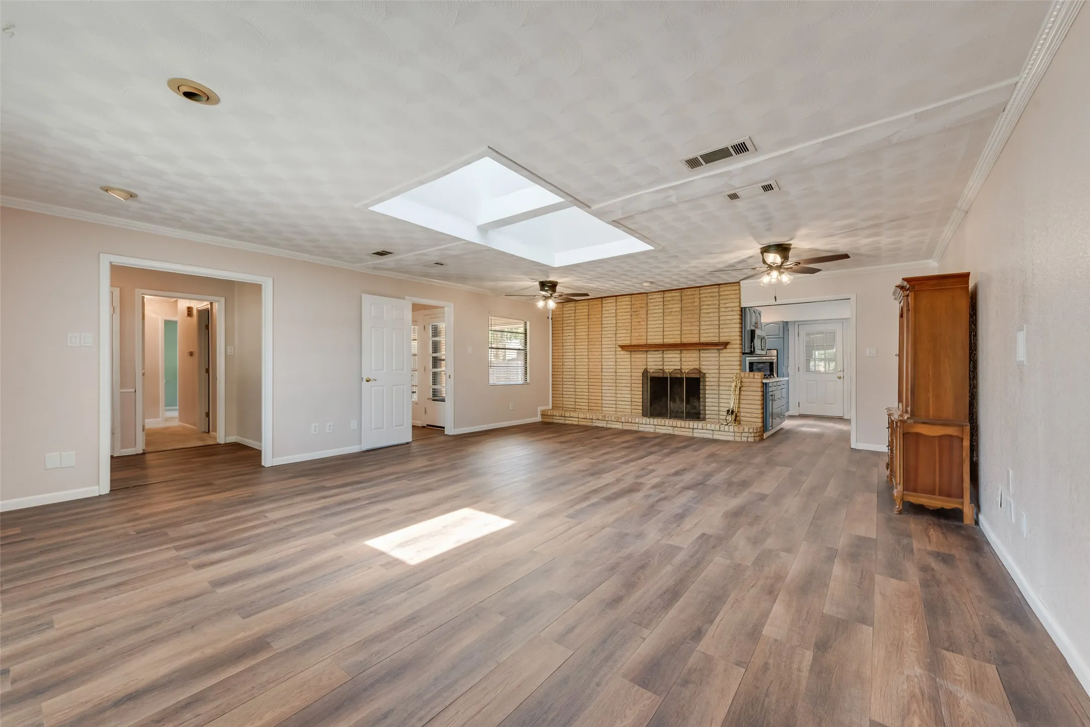 Spacious living area featuring a brick fireplace with a hearth and large skylight