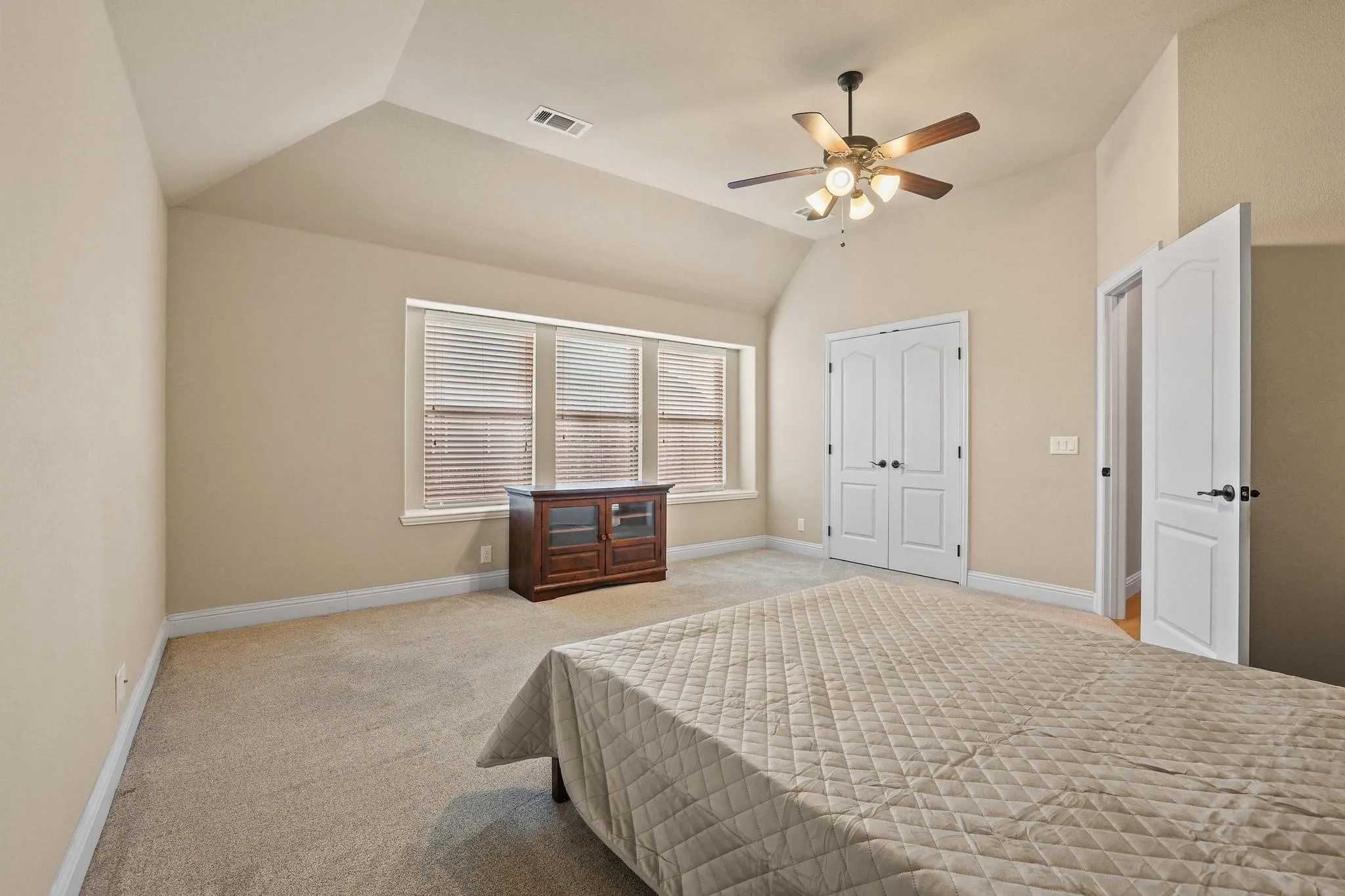 Carpeted room featuring a vaulted ceiling and a ceiling fan with light fixture