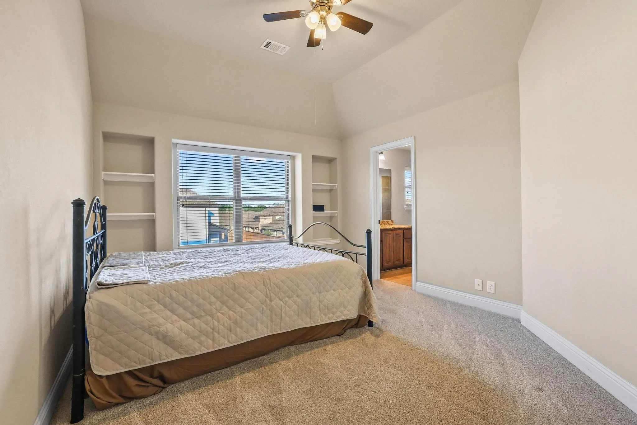 Carpeted room featuring a vaulted ceiling and a ceiling fan with integrated lighting