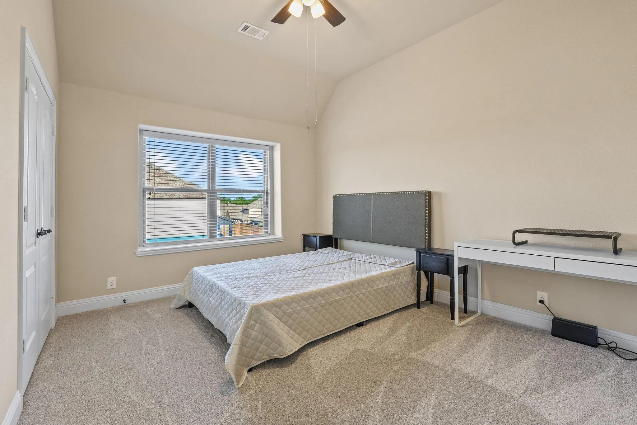 Carpeted room featuring a window with blinds, a vaulted ceiling, and a ceiling fan with integrated lighting