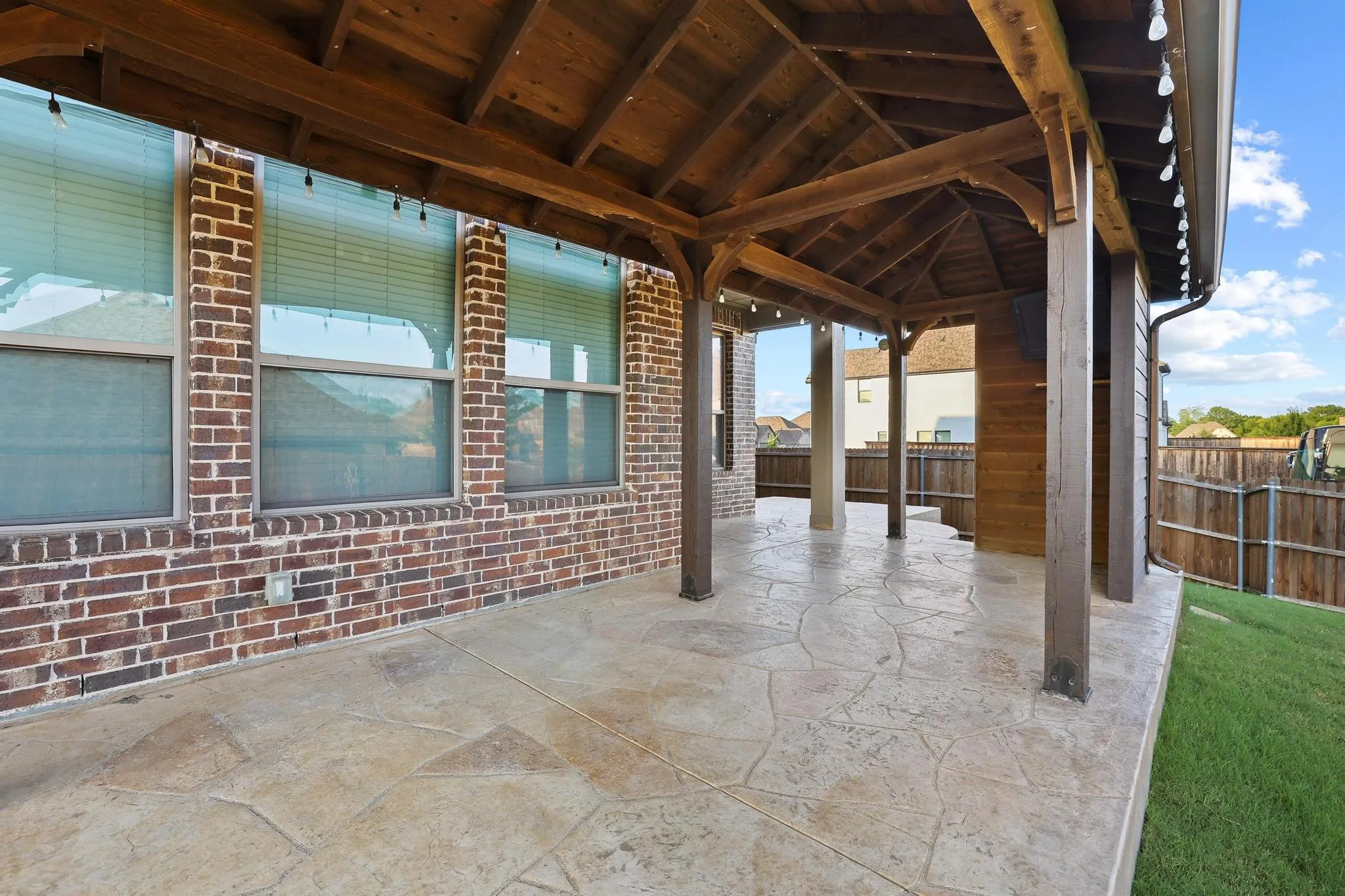 Covered patio featuring a stamped concrete surface and a wood-beamed ceiling