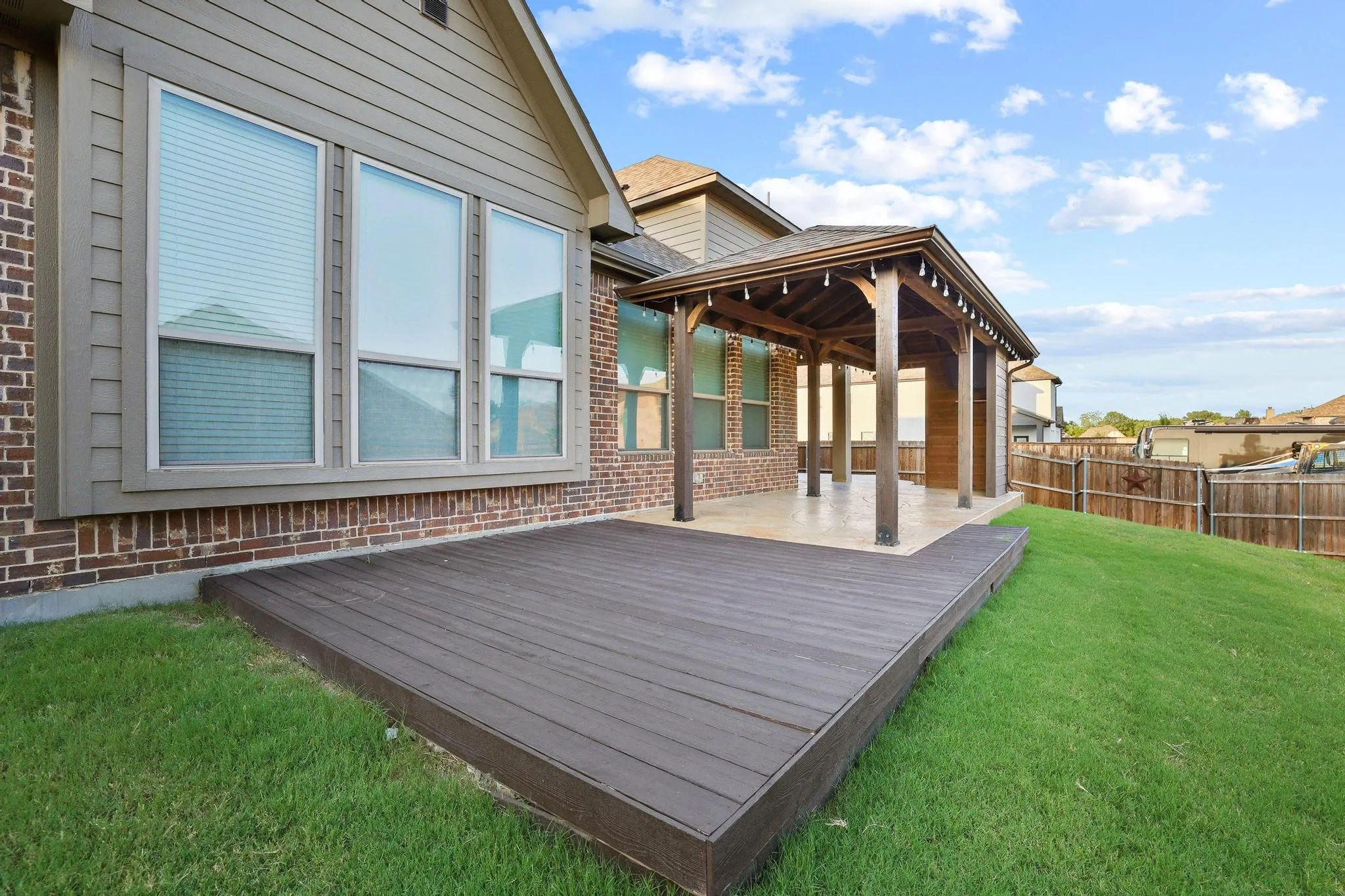 Outdoor living area featuring a wood-finish deck and an attached covered patio with exposed wood beams