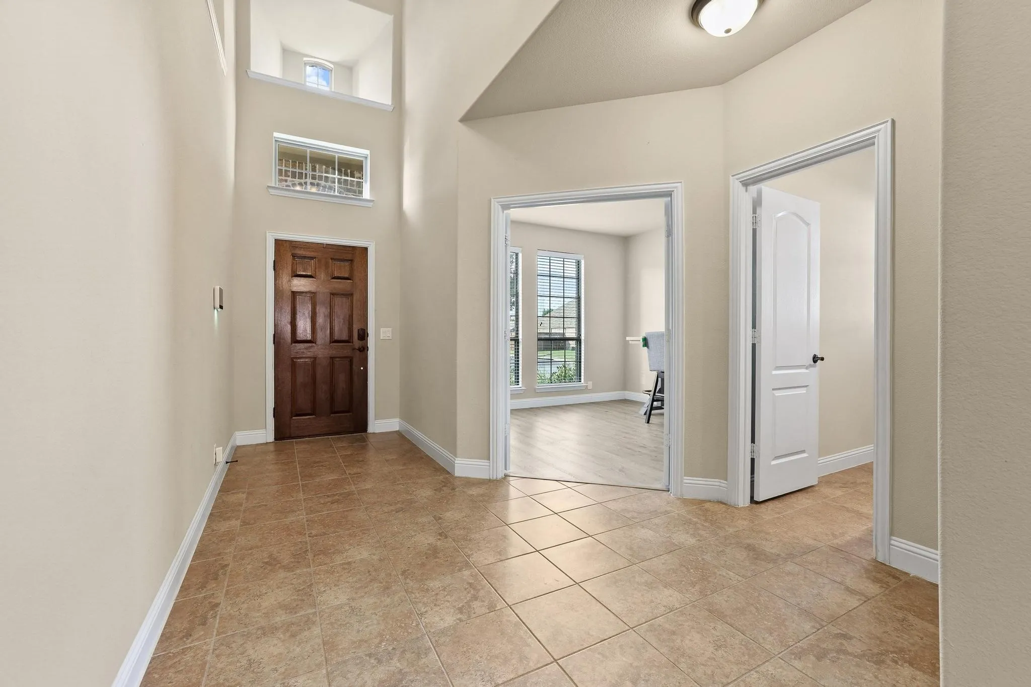 Entryway featuring a paneled wood-finish door, tiled flooring, and high ceilings