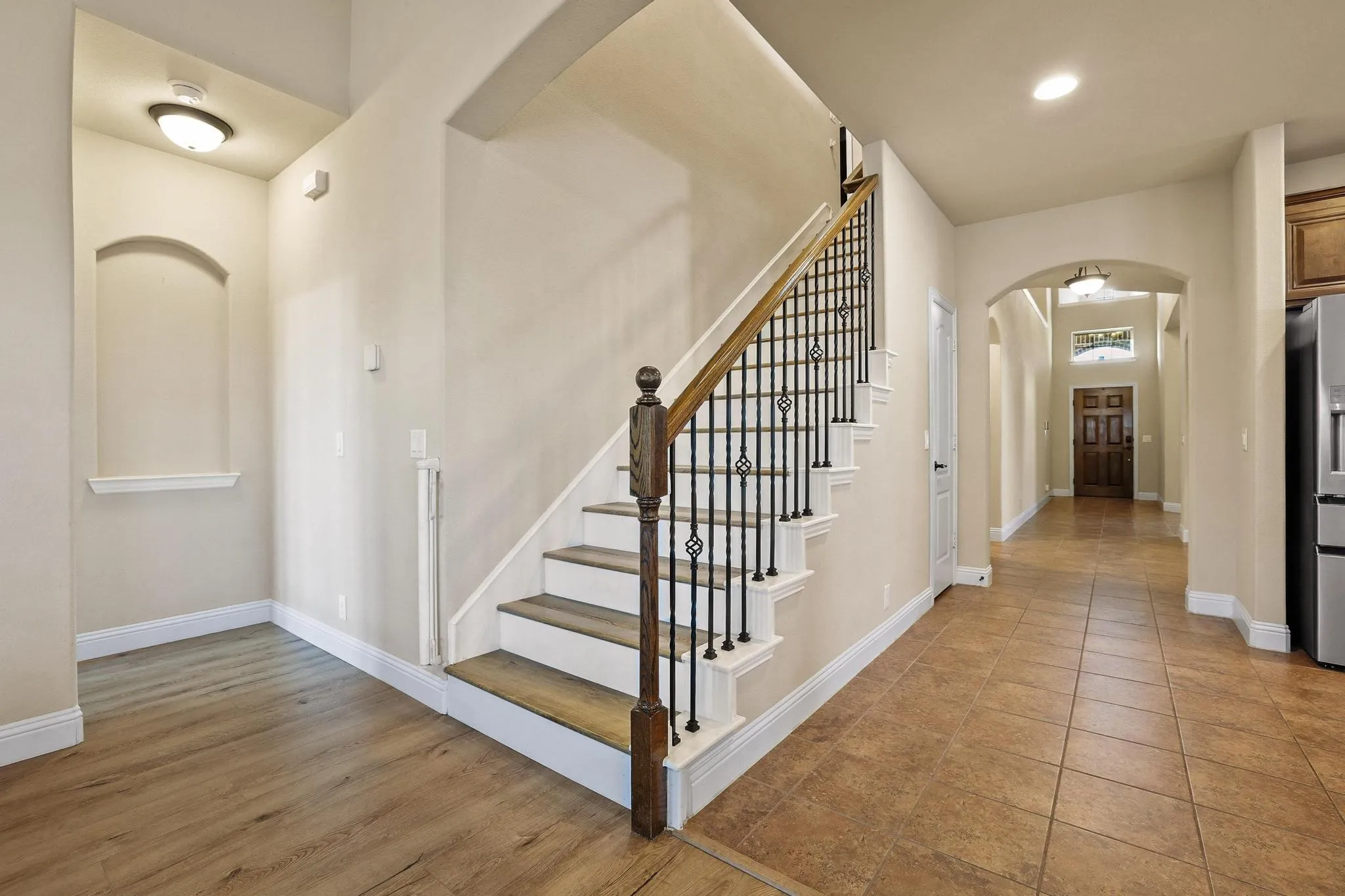 Staircase featuring wood handrail and decorative wrought iron balusters