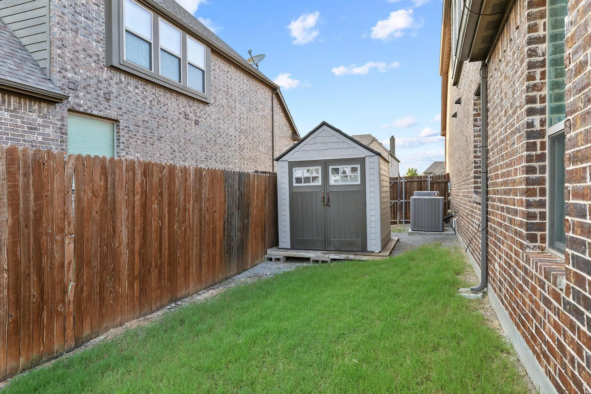 Side yard featuring a storage shed, manicured lawn, and wood privacy fence