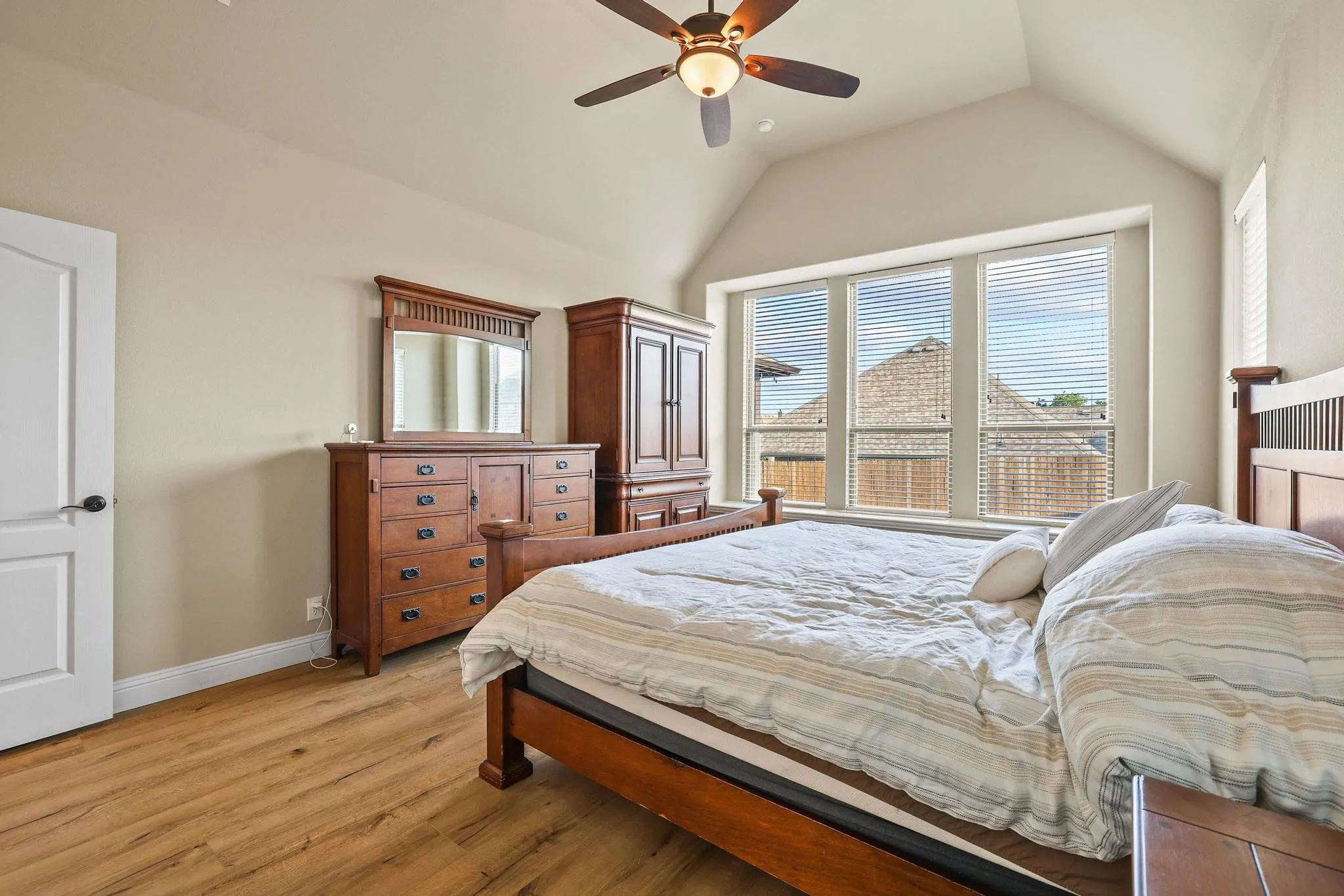 Spacious room with wood-finish flooring, a vaulted ceiling, and an overhead fan with integrated lighting