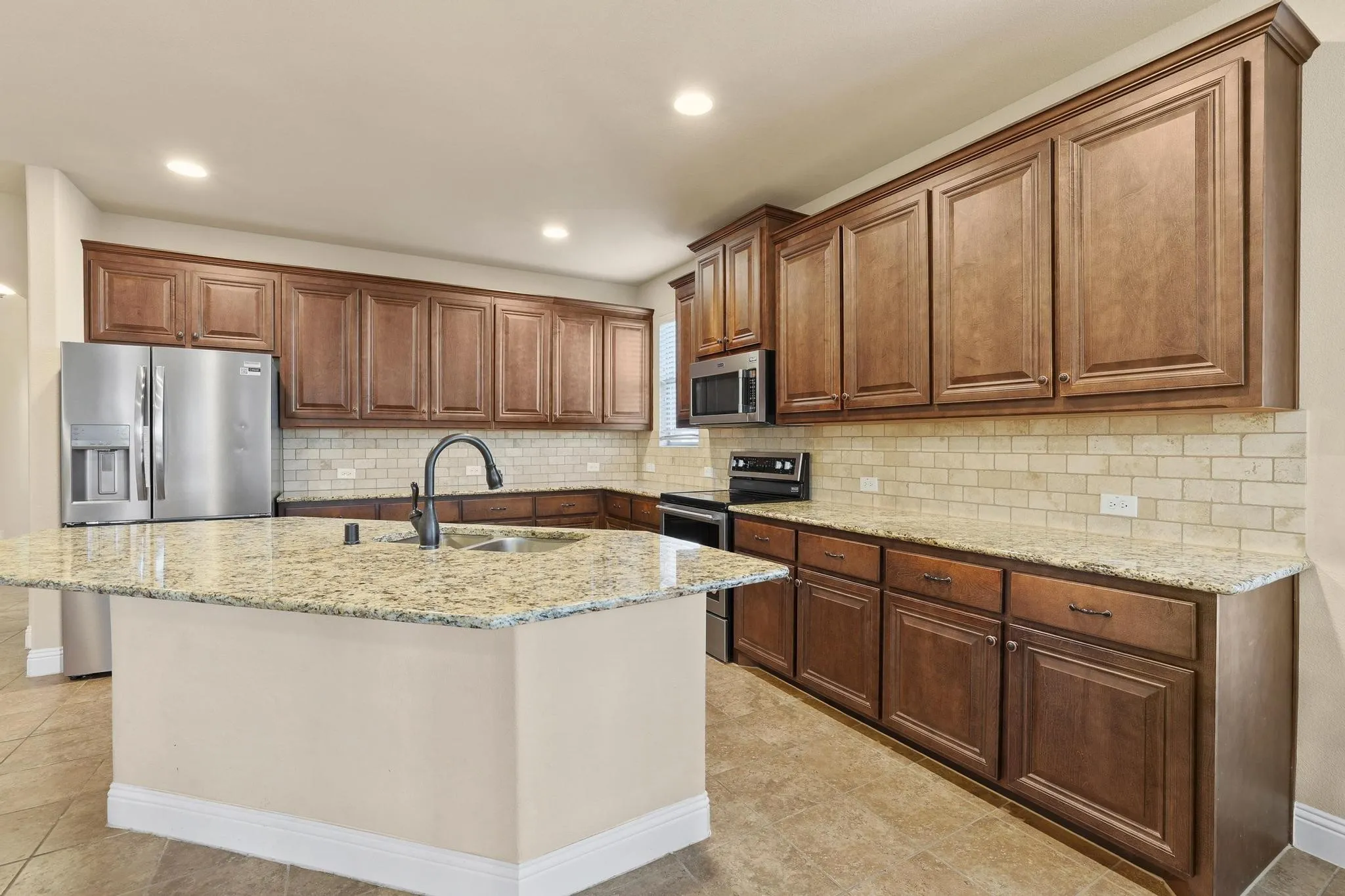 Kitchen featuring an expansive island with a granite countertop, undermount sink, and matte black faucet