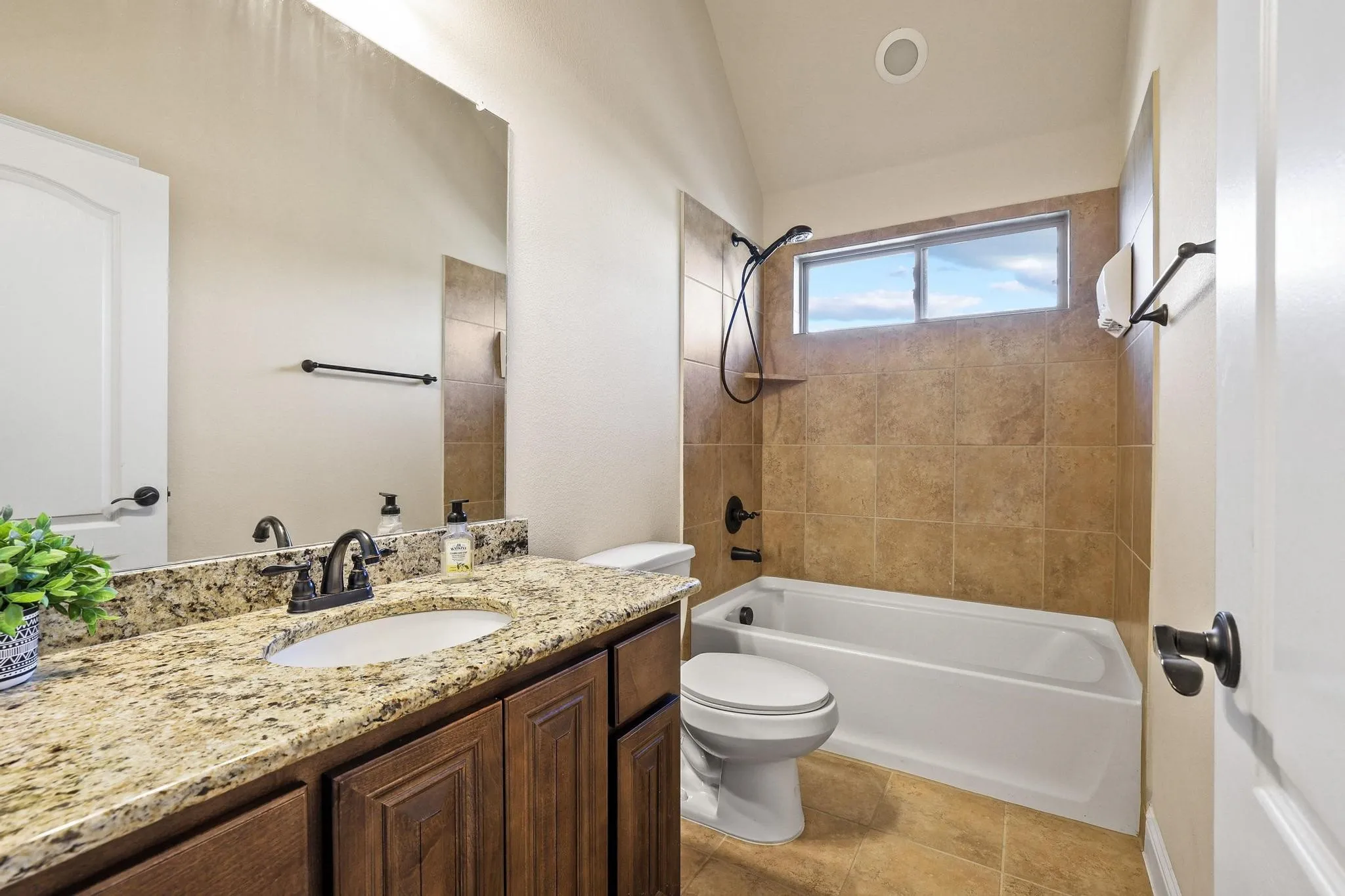 Bathroom featuring a single vanity with a granite countertop, undermount sink, and dark wood-finish cabinetry
