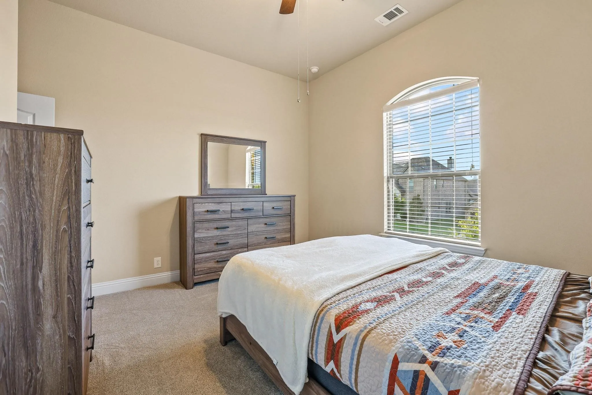Carpeted room featuring a vaulted ceiling and an arched window with blinds