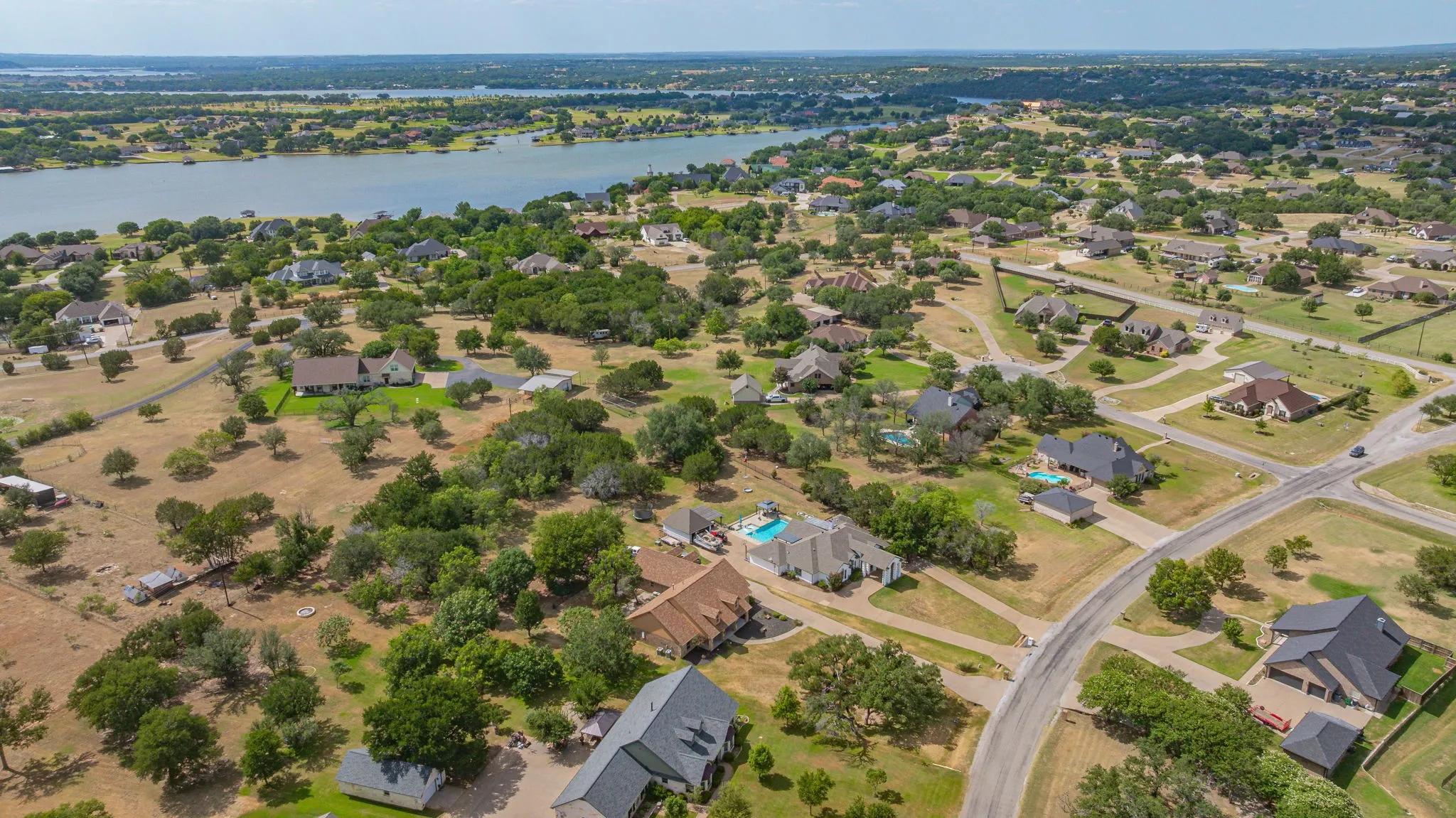 Expansive aerial perspective showcasing a residential landscape with a prominent body of water in the background