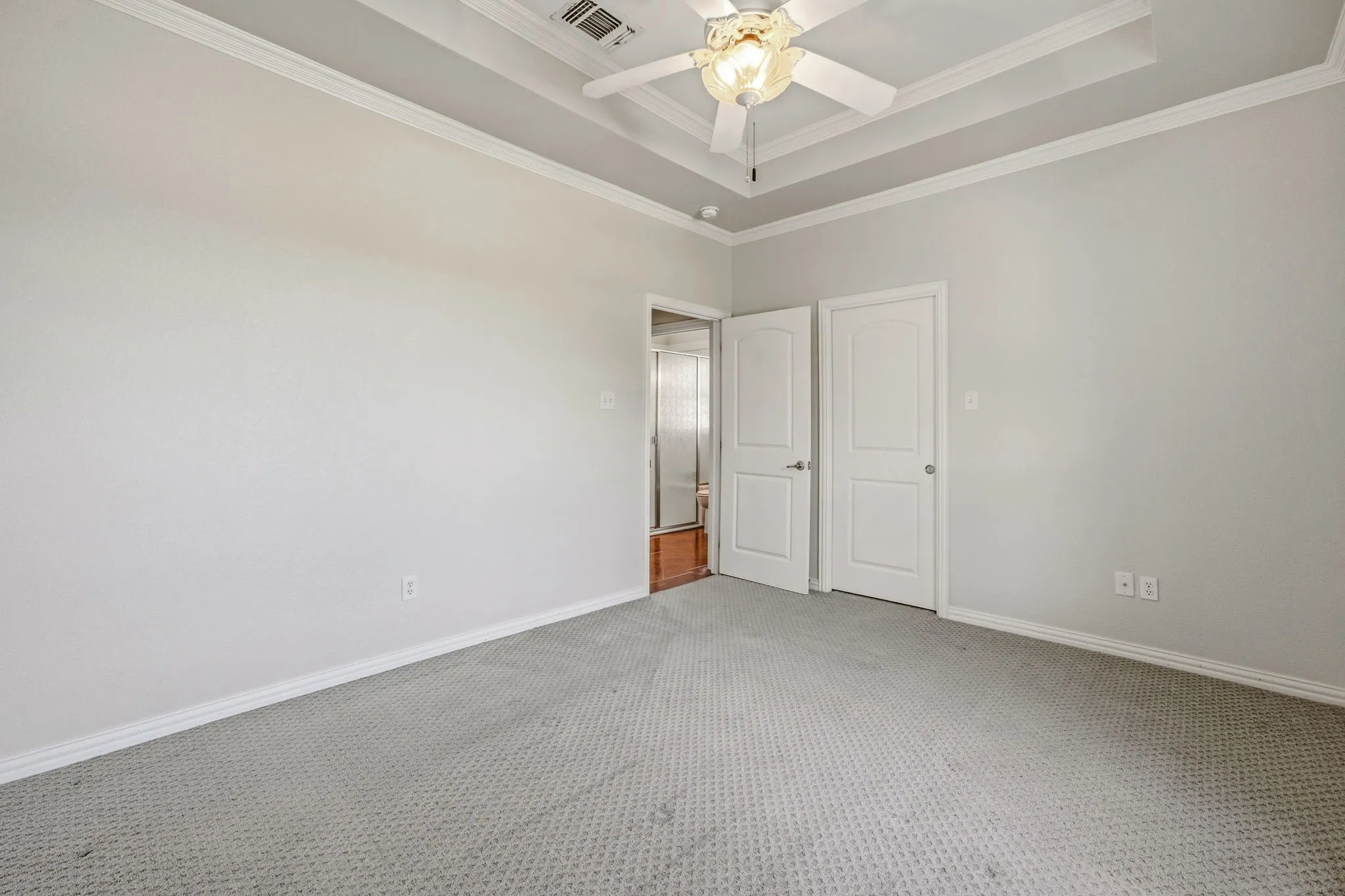 Tray ceiling with crown molding, ceiling fan, grey carpet flooring, and white trim