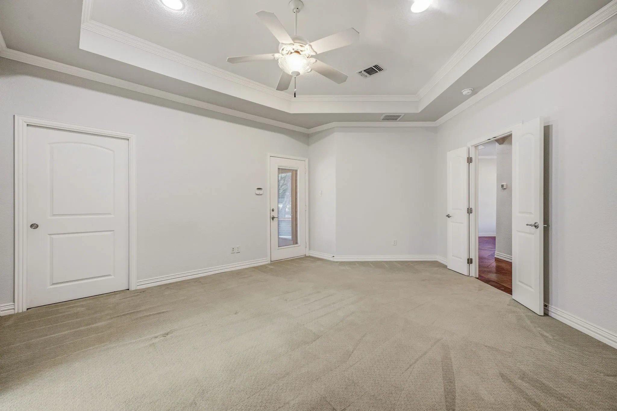 Spacious room featuring tray ceilings, a ceiling fan, recessed lighting, and light-toned carpeting