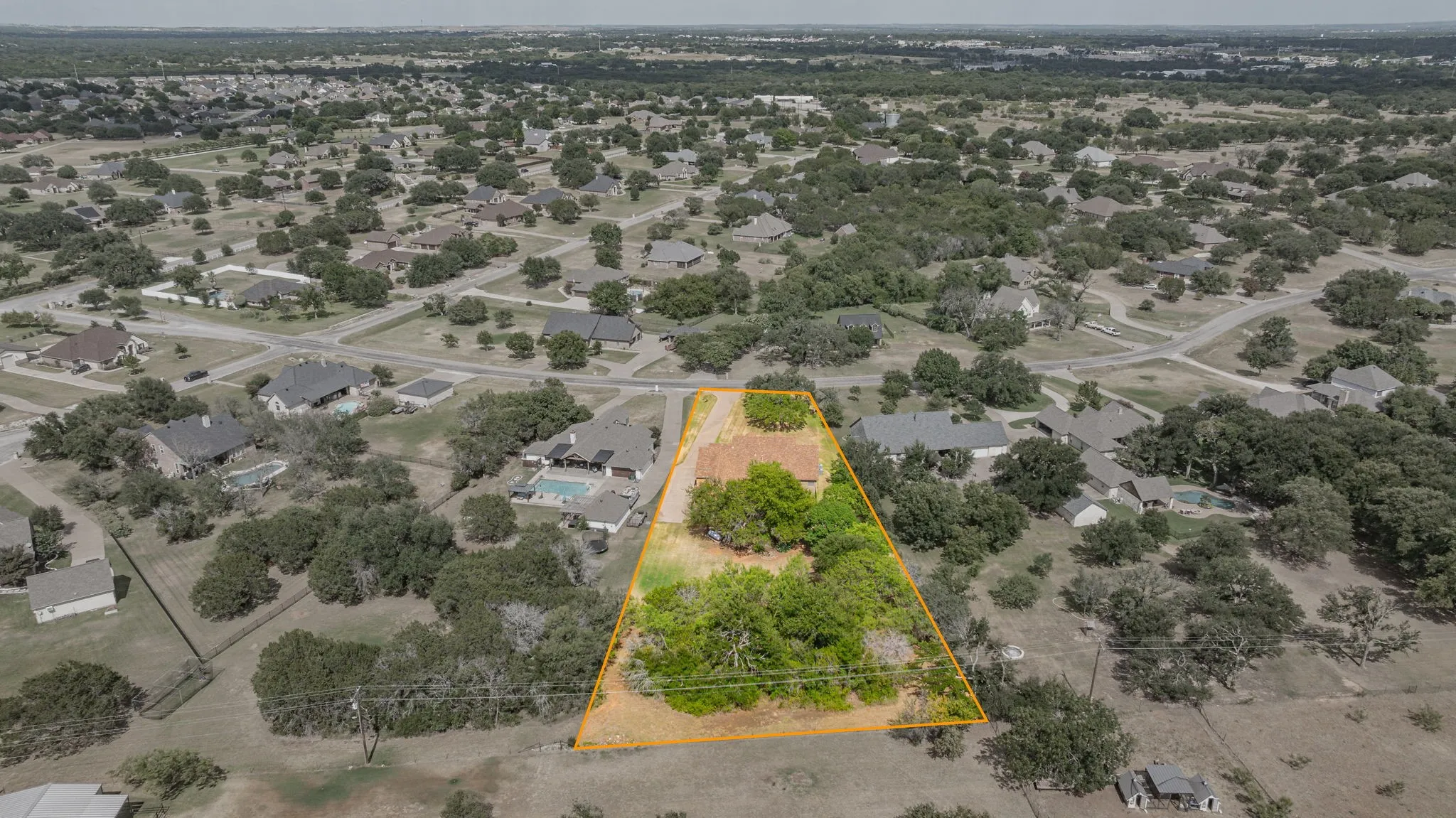 Aerial view showcasing a residential property with established trees and a defined lot boundary