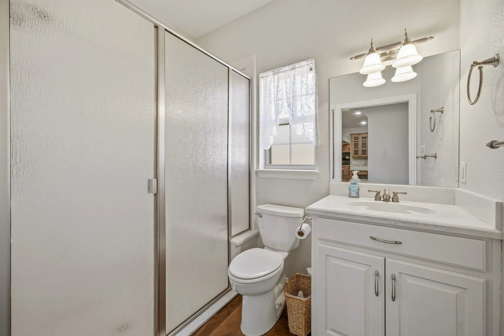 Bathroom featuring a white vanity with a single basin, a framed mirror, and a wall-mounted light fixture