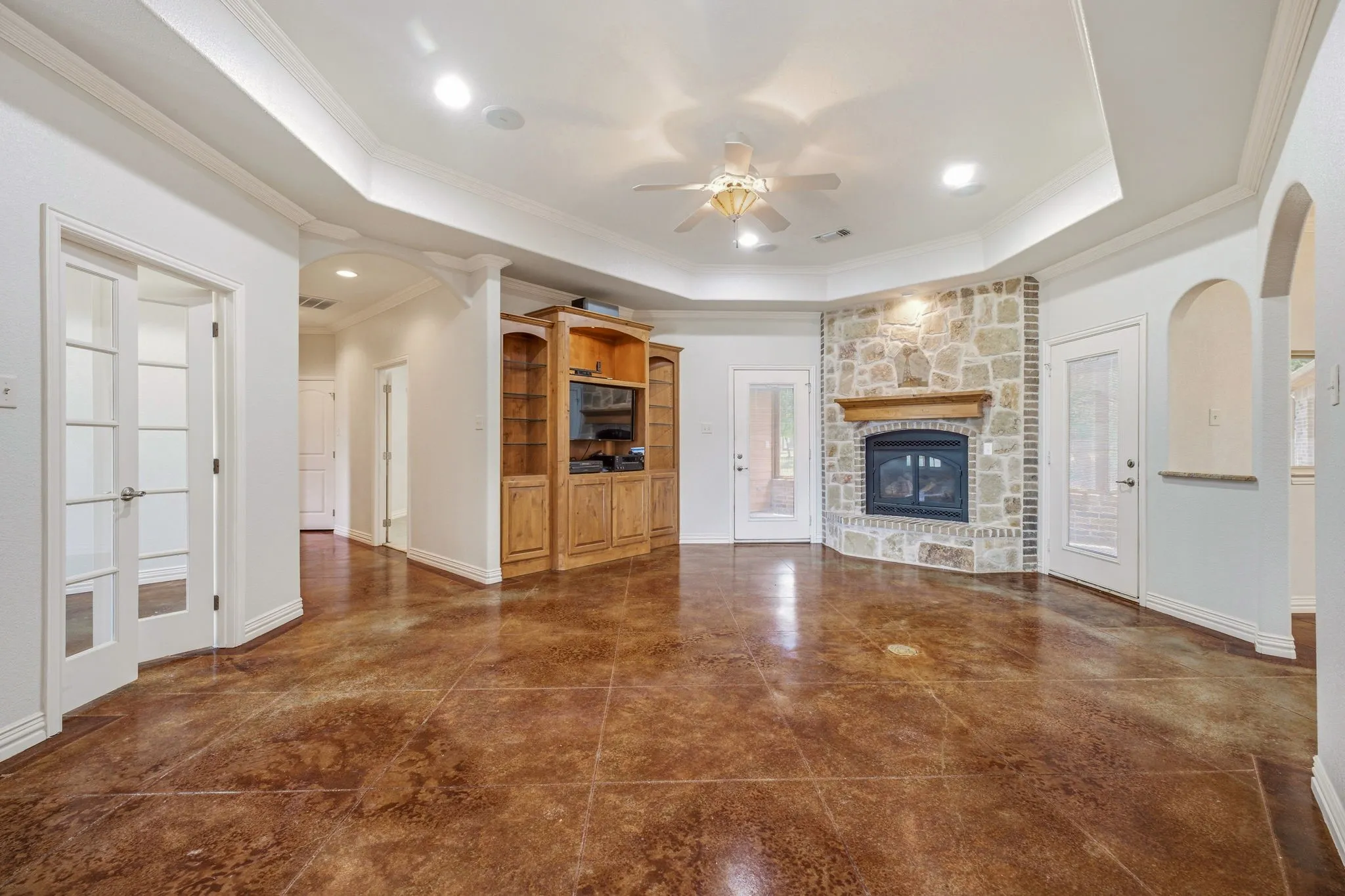 Spacious interior featuring a stone fireplace with wood mantel, built-in entertainment center, coffered ceiling, and wood-finish flooring