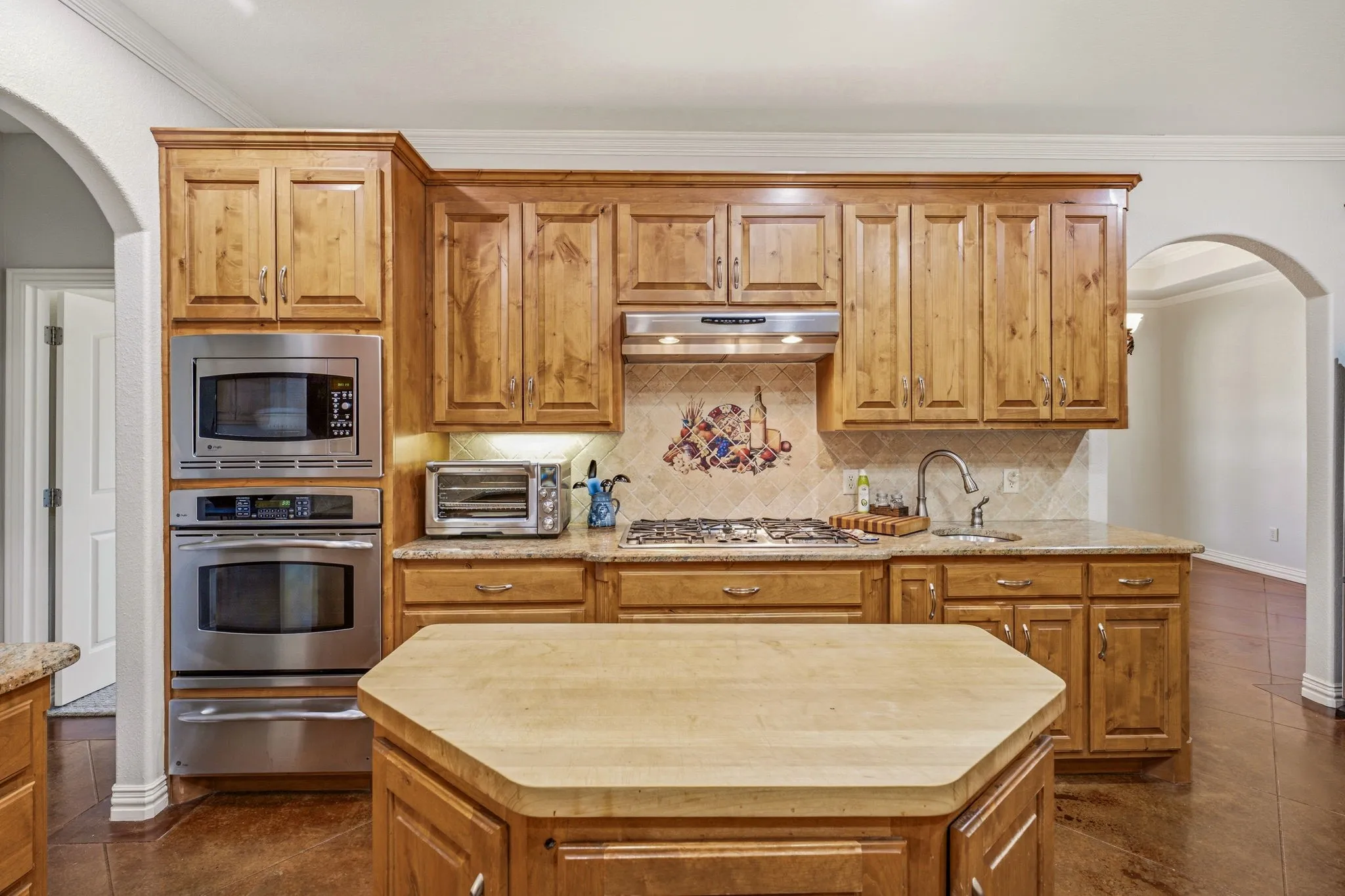 Kitchen featuring wood cabinetry, stainless steel appliances, a gas cooktop, stone countertops, and a central island with a solid surface top