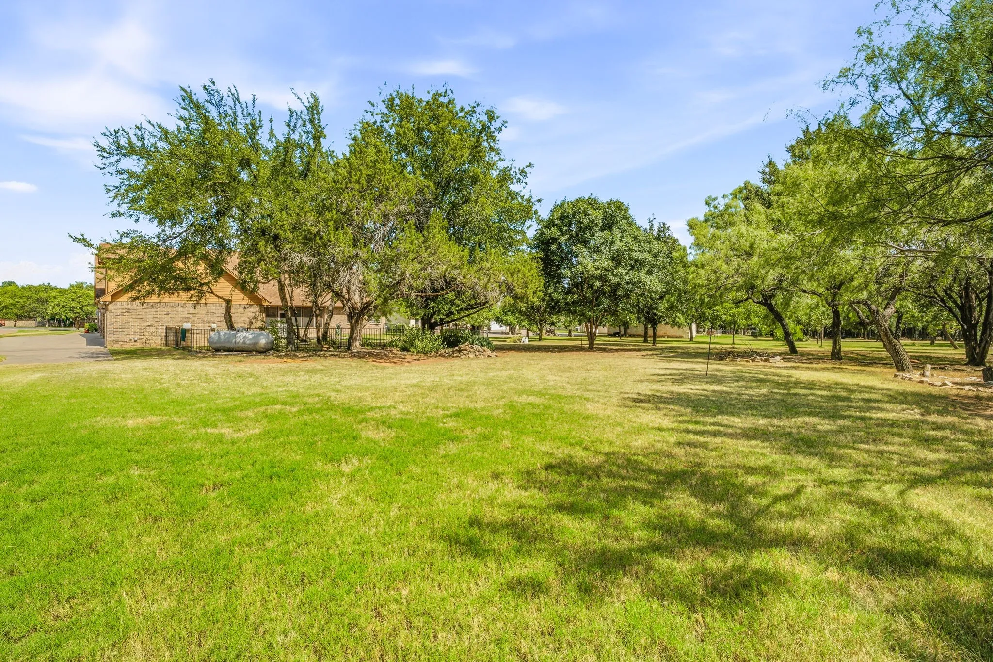 Expansive green lawn with mature trees providing shade