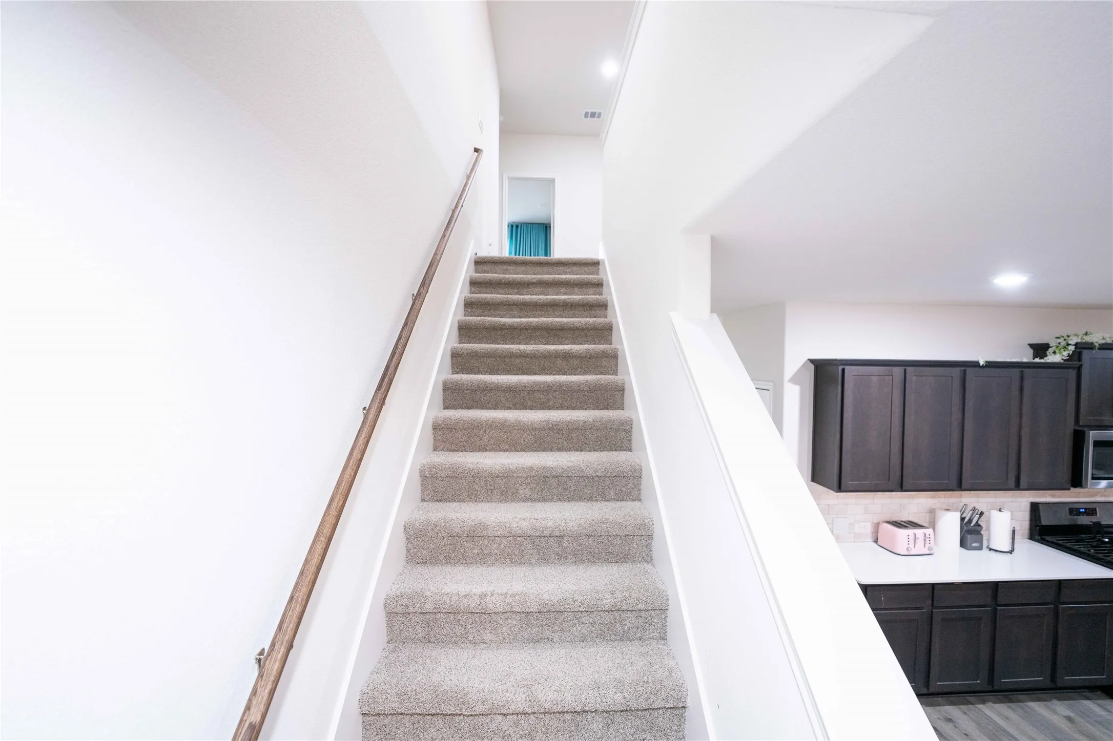 Carpeted staircase with a wood-finish handrail and integrated lighting