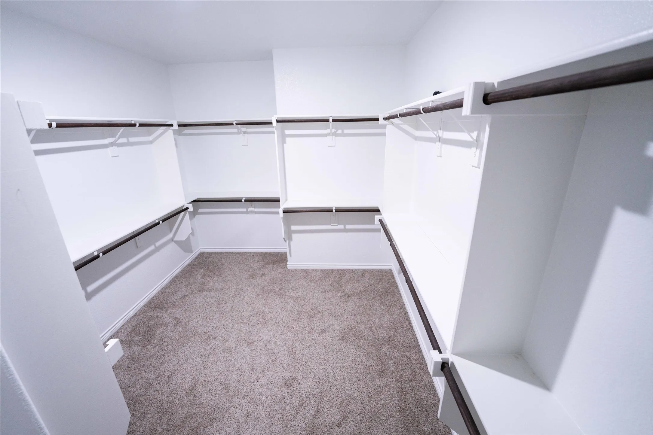 Spacious walk-in closet featuring extensive built-in shelving and multiple dark-finish clothing rods