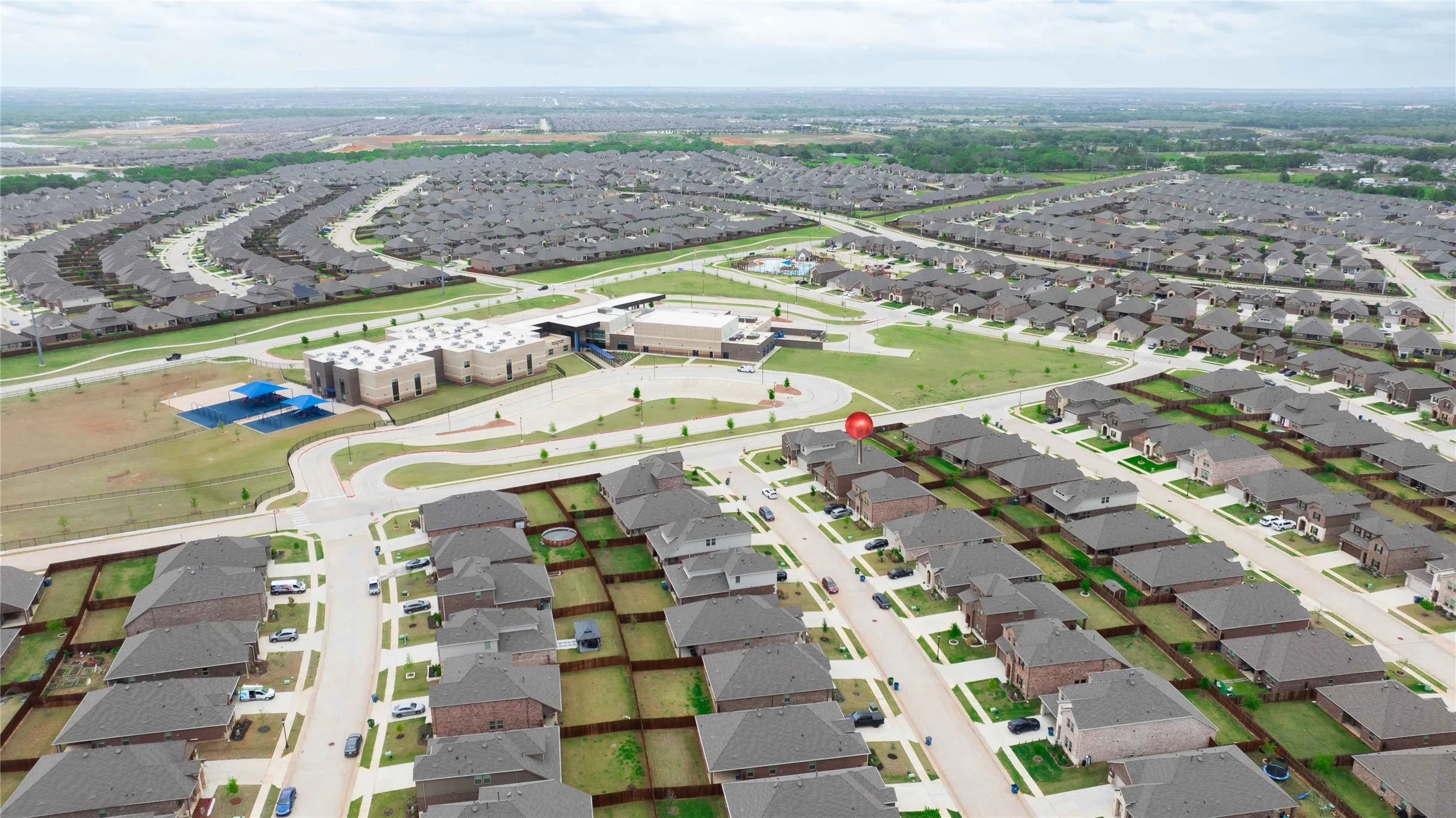Aerial perspective of a developed residential area featuring a central institutional building