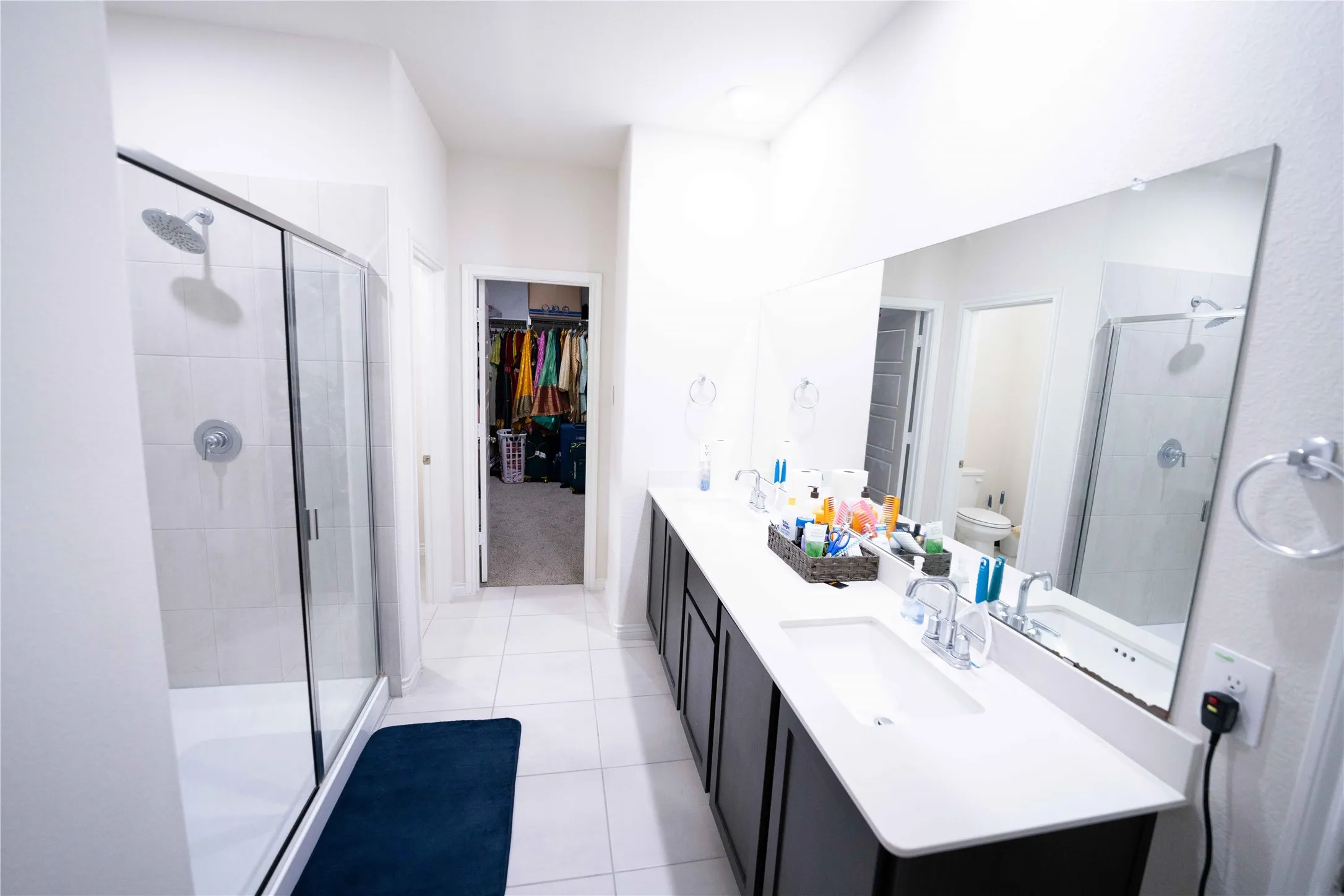 Bathroom featuring a dual vanity with a white countertop, chrome fixtures, and a frameless mirror