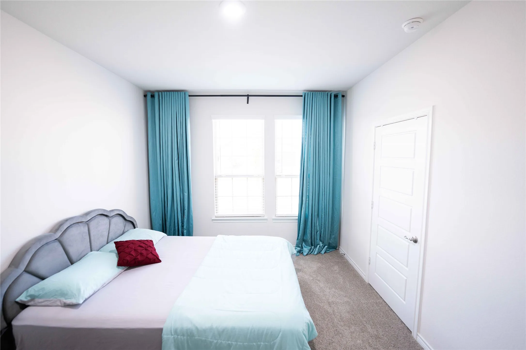 Bright interior room featuring white walls and a light-colored carpet