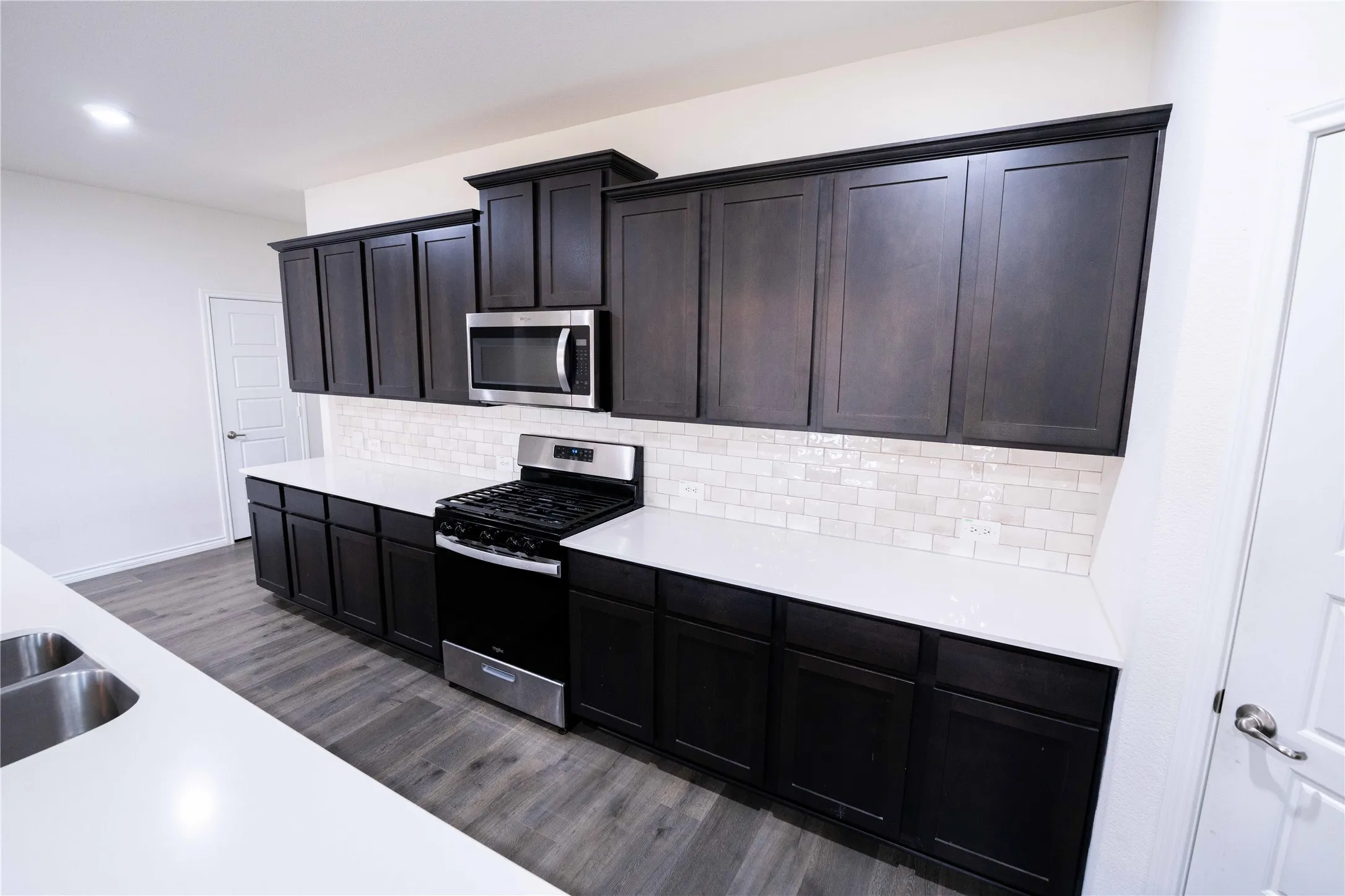Kitchen featuring dark wood-finish cabinetry, stainless steel appliances, and light countertops