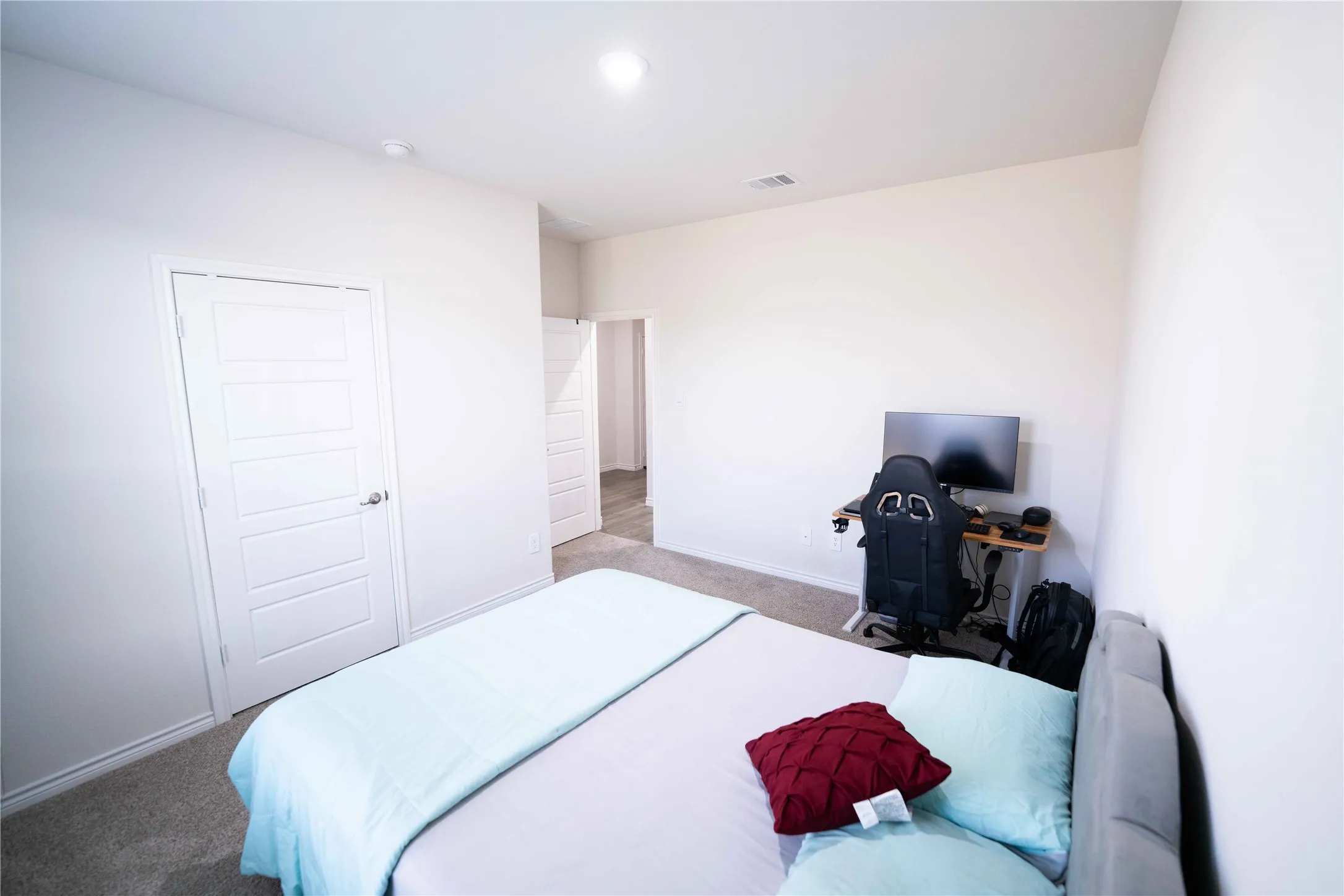Bright room featuring neutral-toned walls, gray carpeting, and a modern five-panel interior door
