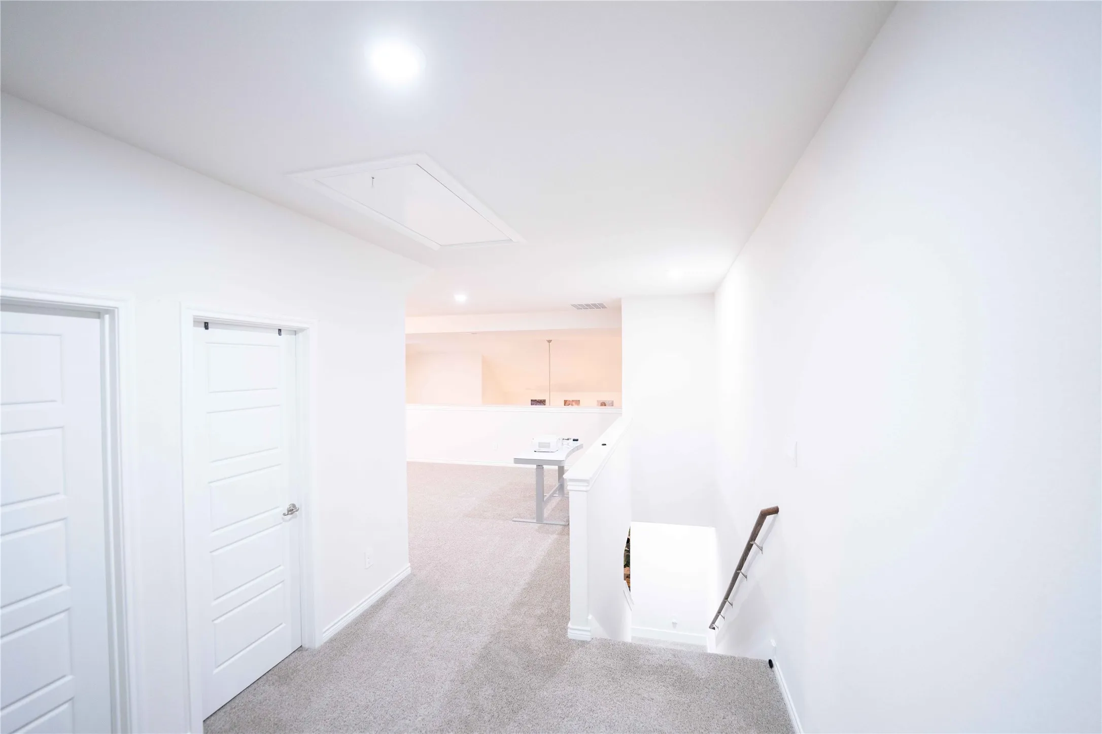 Upper-level hallway featuring light gray carpeting and recessed lighting
