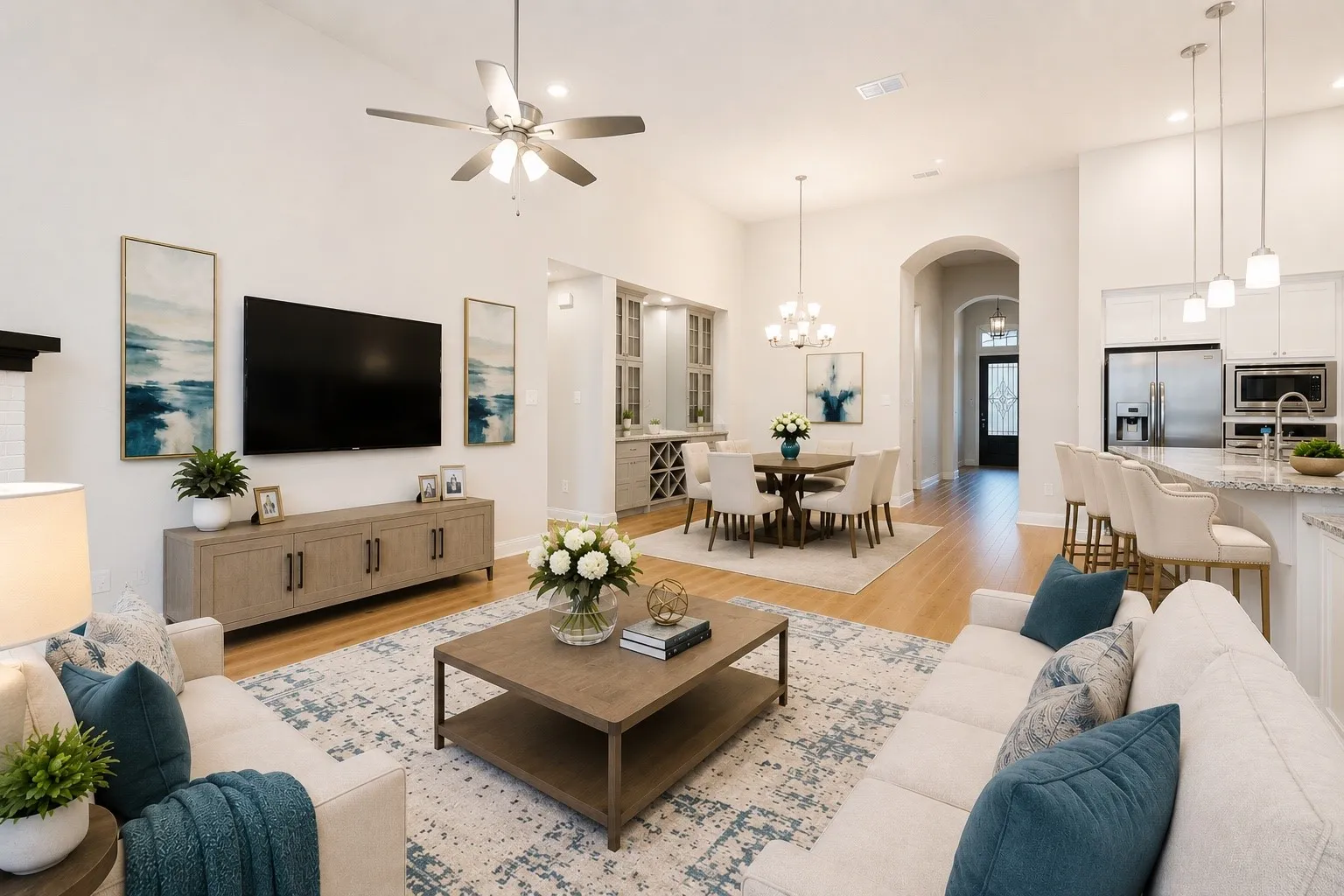 Expansive living area featuring vaulted ceilings, wood-finish flooring, an open-concept layout, a kitchen island with bar seating, and a dining area with chandelier lighting