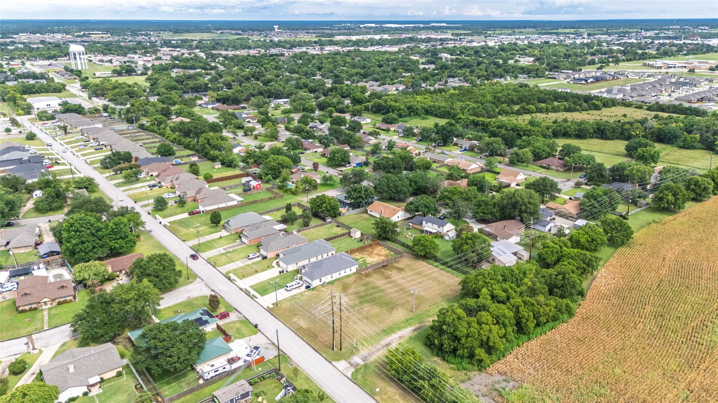 Expansive aerial perspective showcasing a residential development bordered by open fields and mature trees