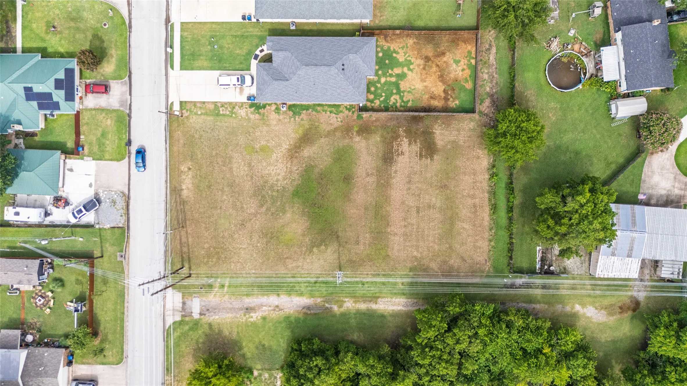 Cleared lot with street frontage and mature trees bordering the rear