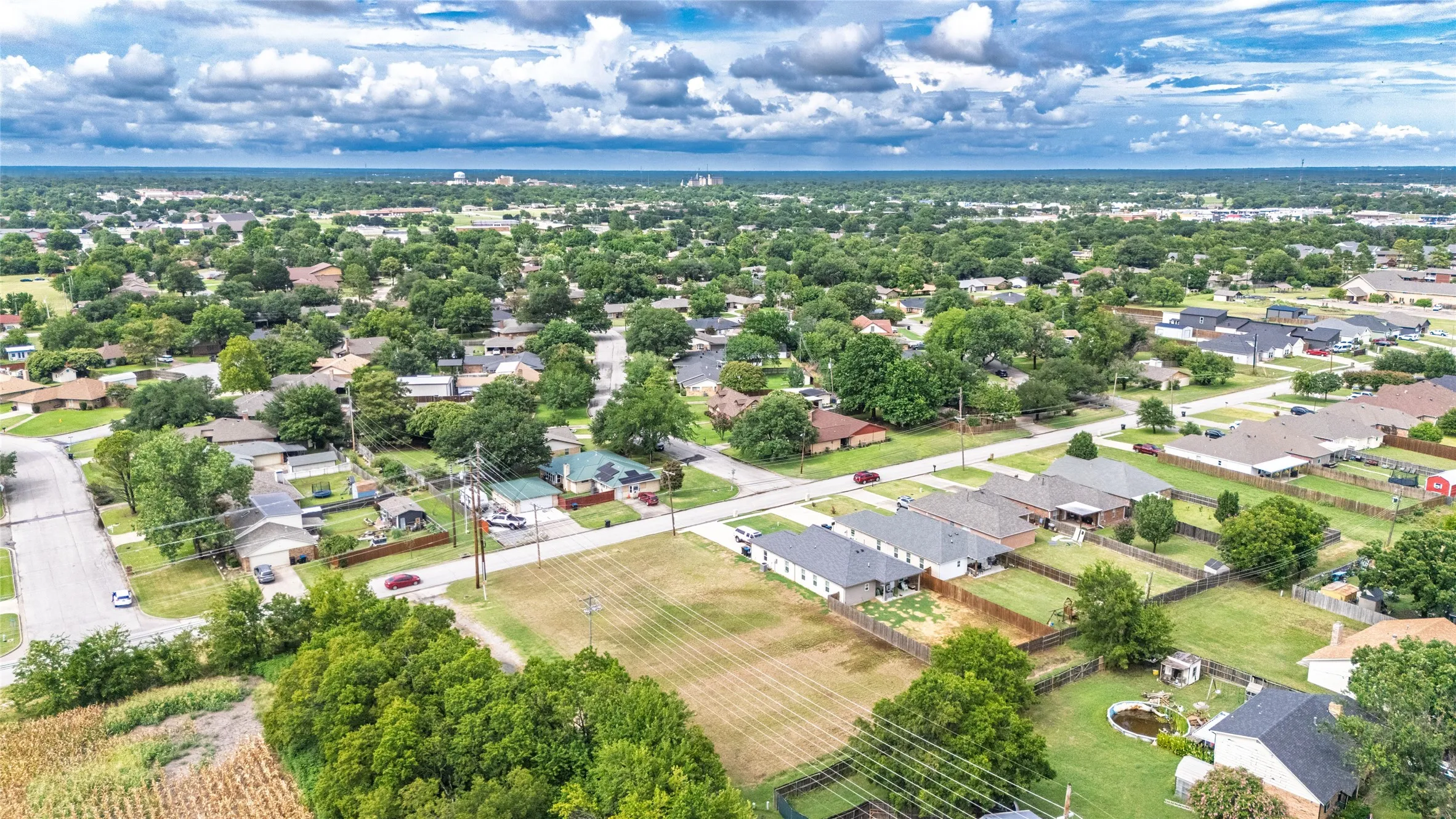 Expansive residential area featuring numerous single-story homes, mature trees, open green spaces, and paved streets