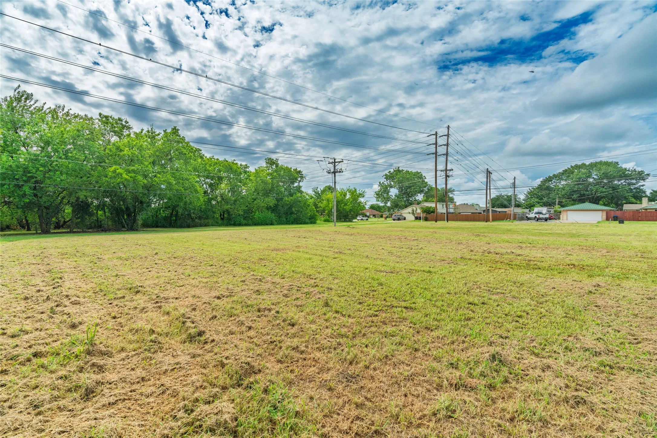 Expansive grassy lot with mature perimeter trees