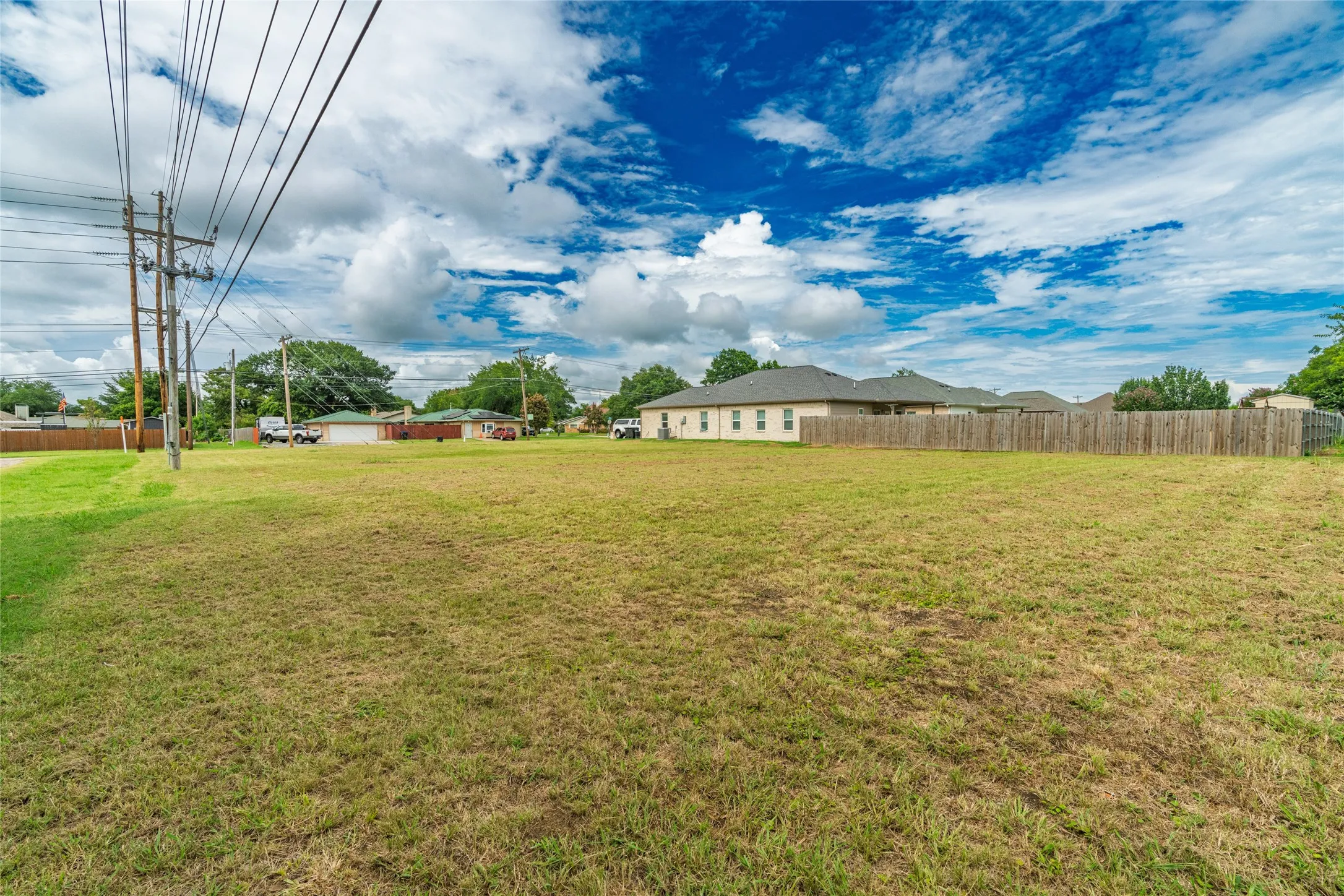 Expansive grassy lot with surrounding wood privacy fencing