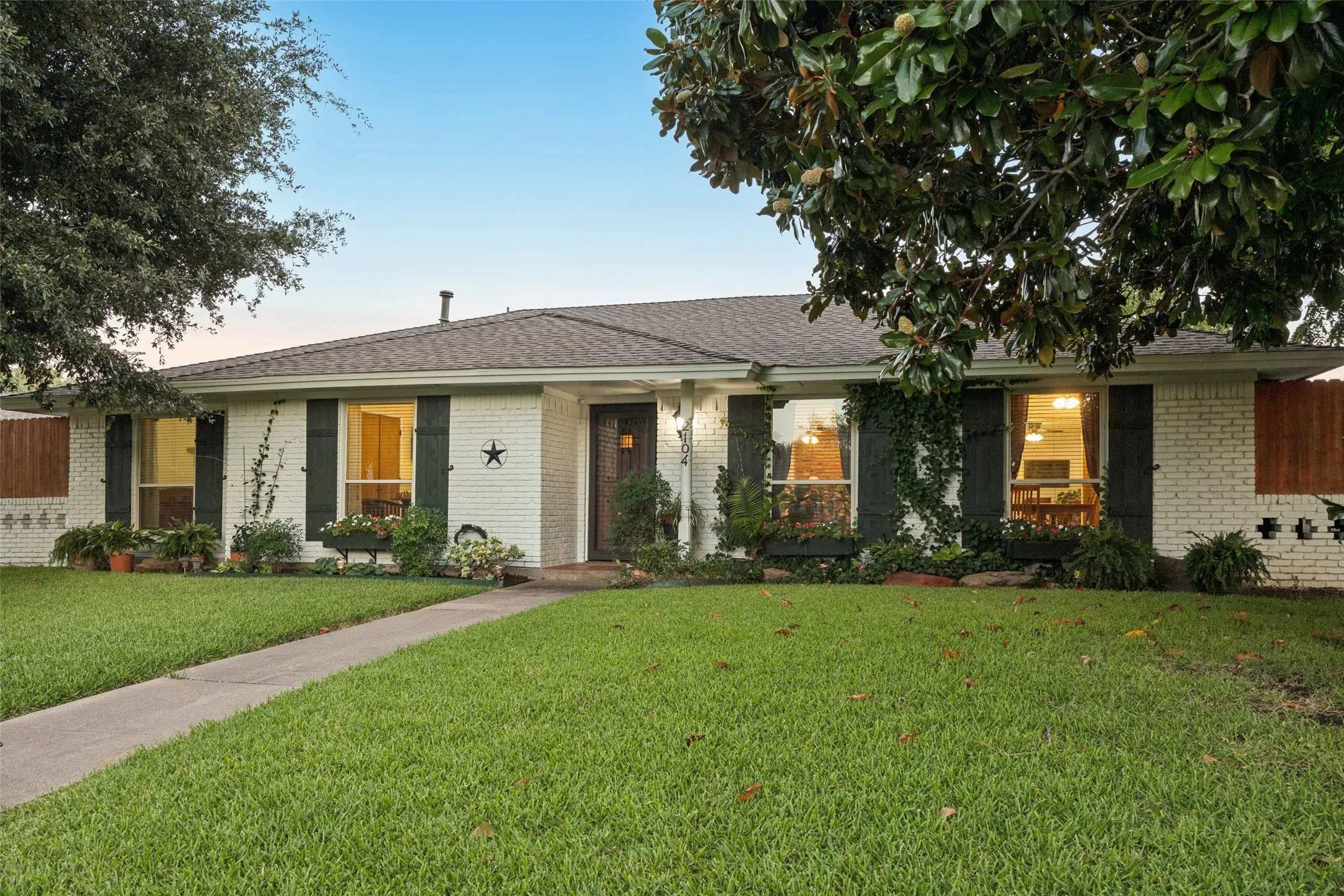 White brick facade featuring dark shutters and a wood front door
