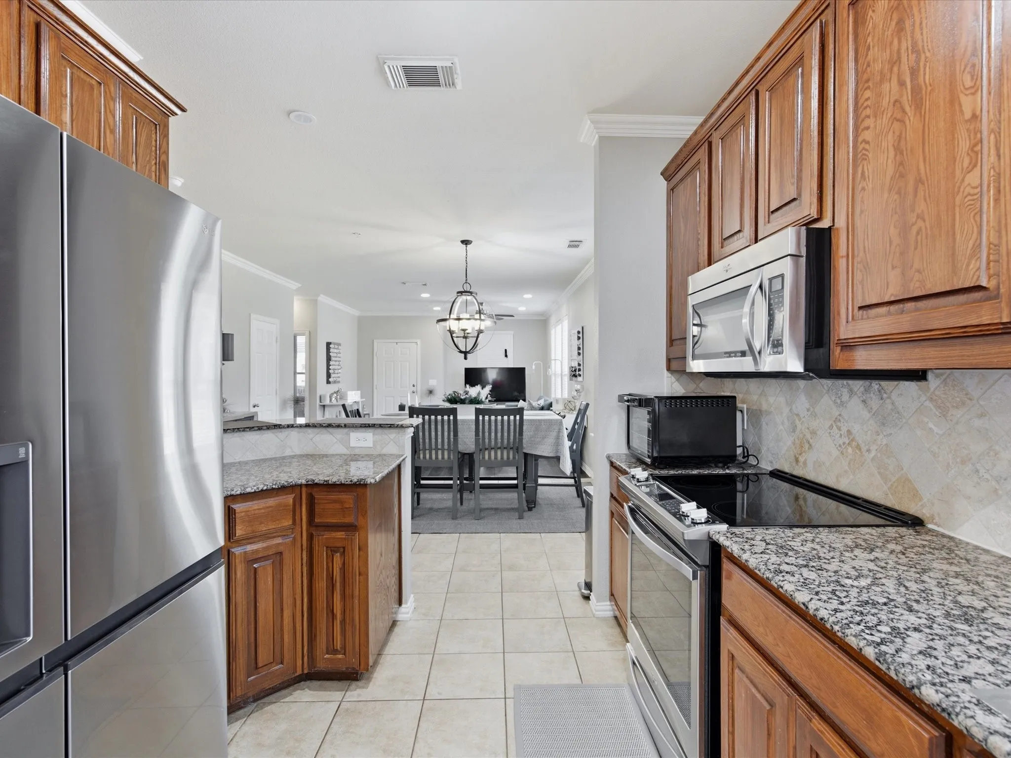 Kitchen featuring wood cabinetry, stainless steel appliances, granite countertops, and a tiled backsplash