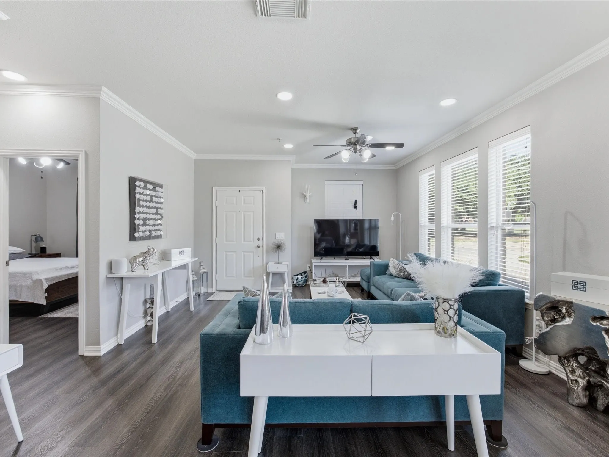 Spacious living area featuring wood-finish flooring, recessed lighting, and multiple windows with blinds