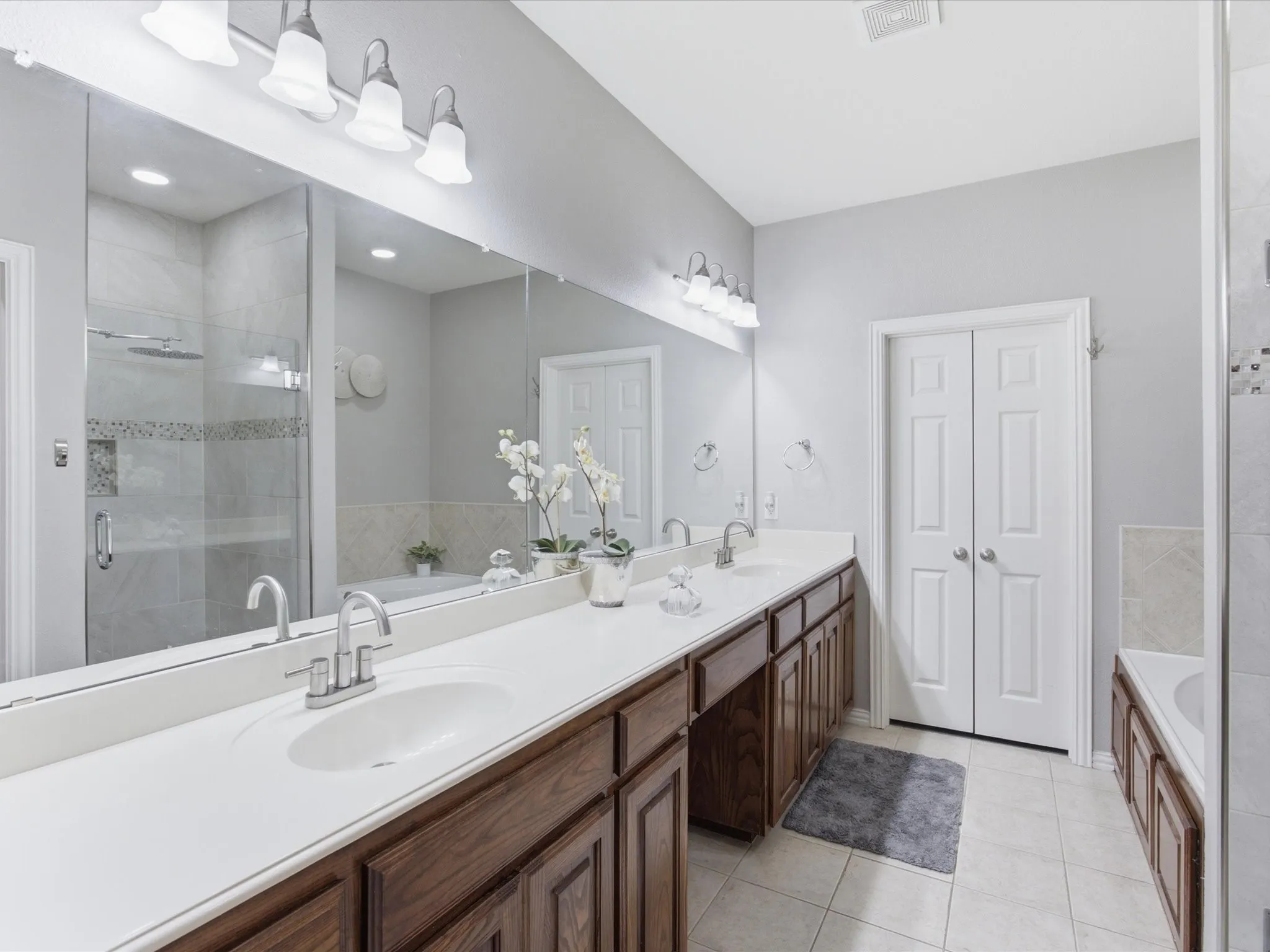 Dual vanity with white countertops and wood-finish cabinetry