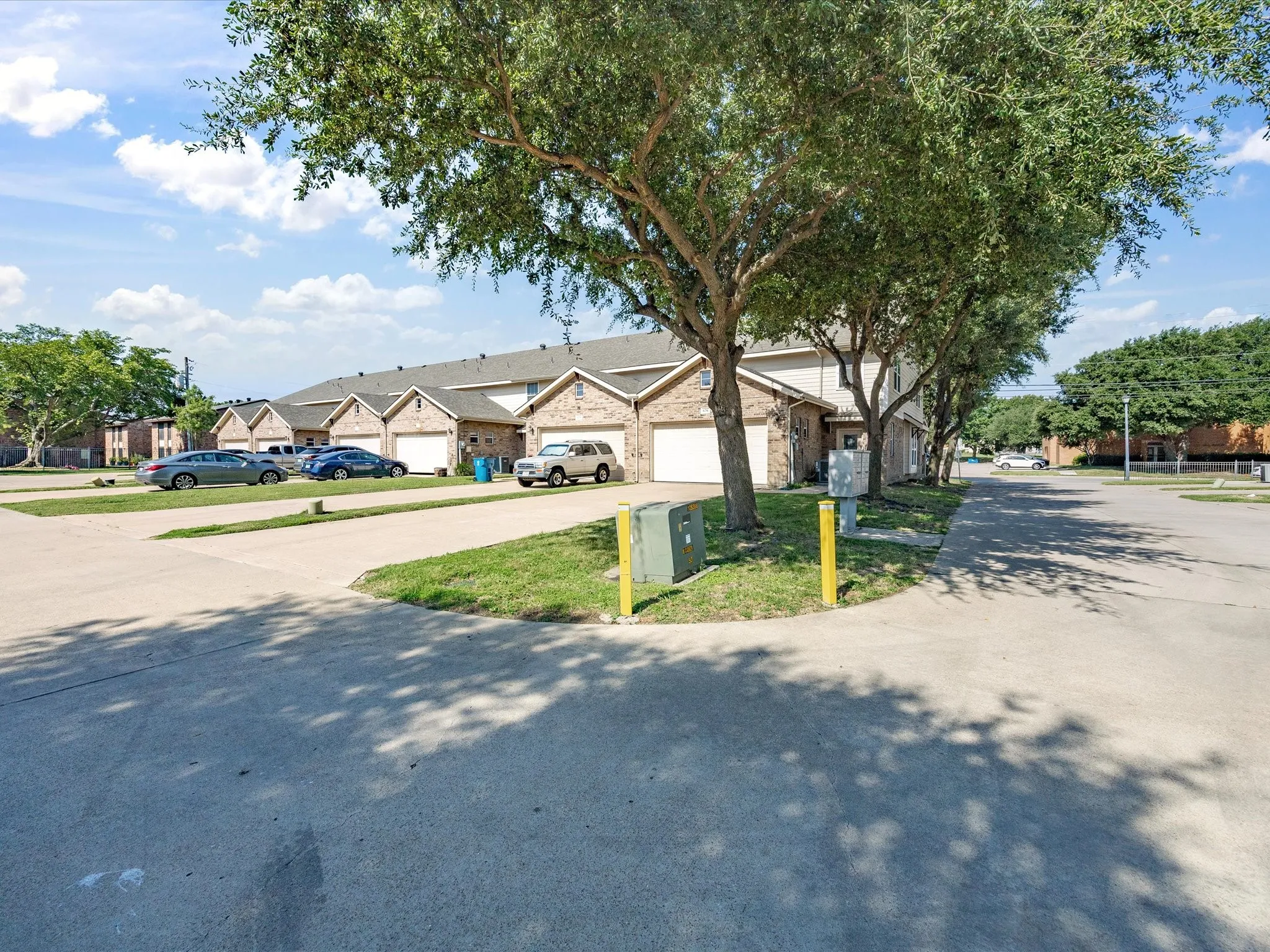 Rear-entry to an attached garage, paved driveway, and established trees