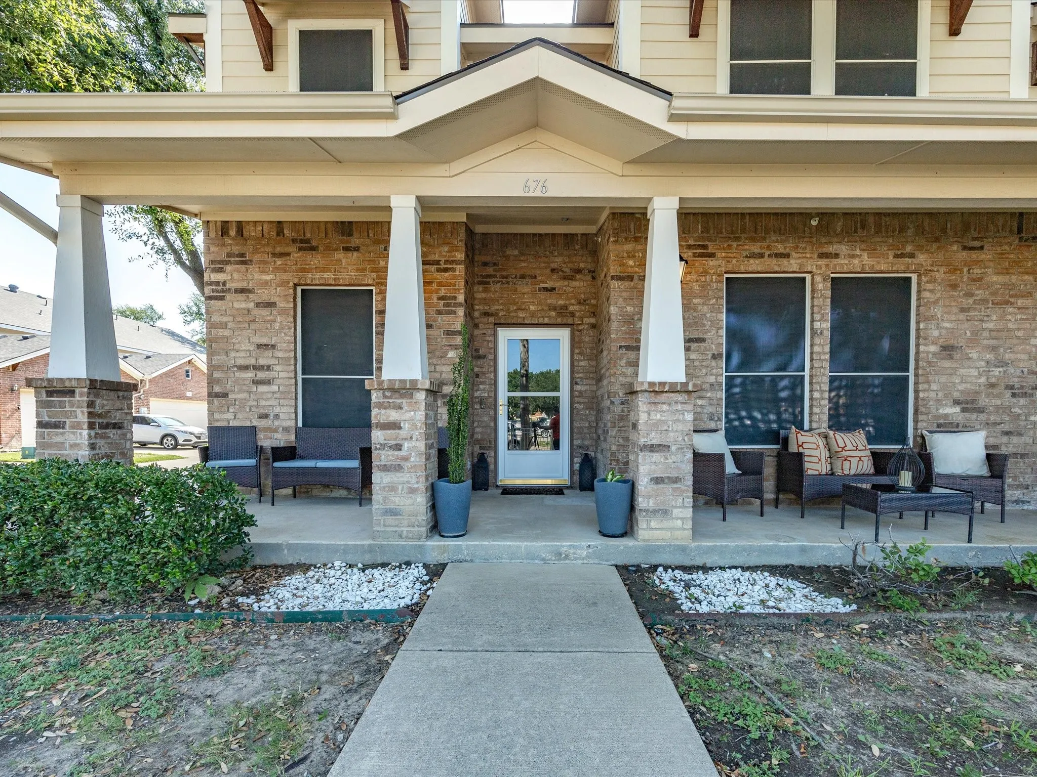 Brick exterior featuring a covered front porch with substantial columns and a prominent entryway