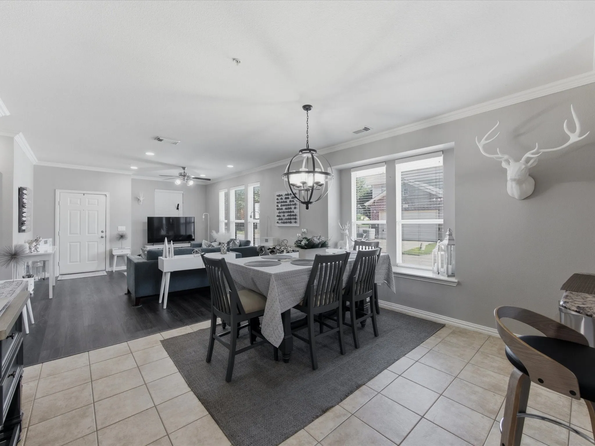 Open-concept dining and living areas featuring a chandelier, tile flooring, wood-finish flooring, and multiple windows