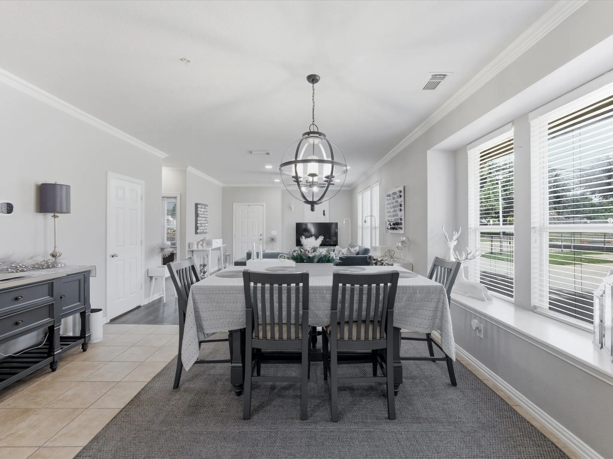Dining area featuring a contemporary spherical chandelier, multiple windows with blinds, and a built-in window bench